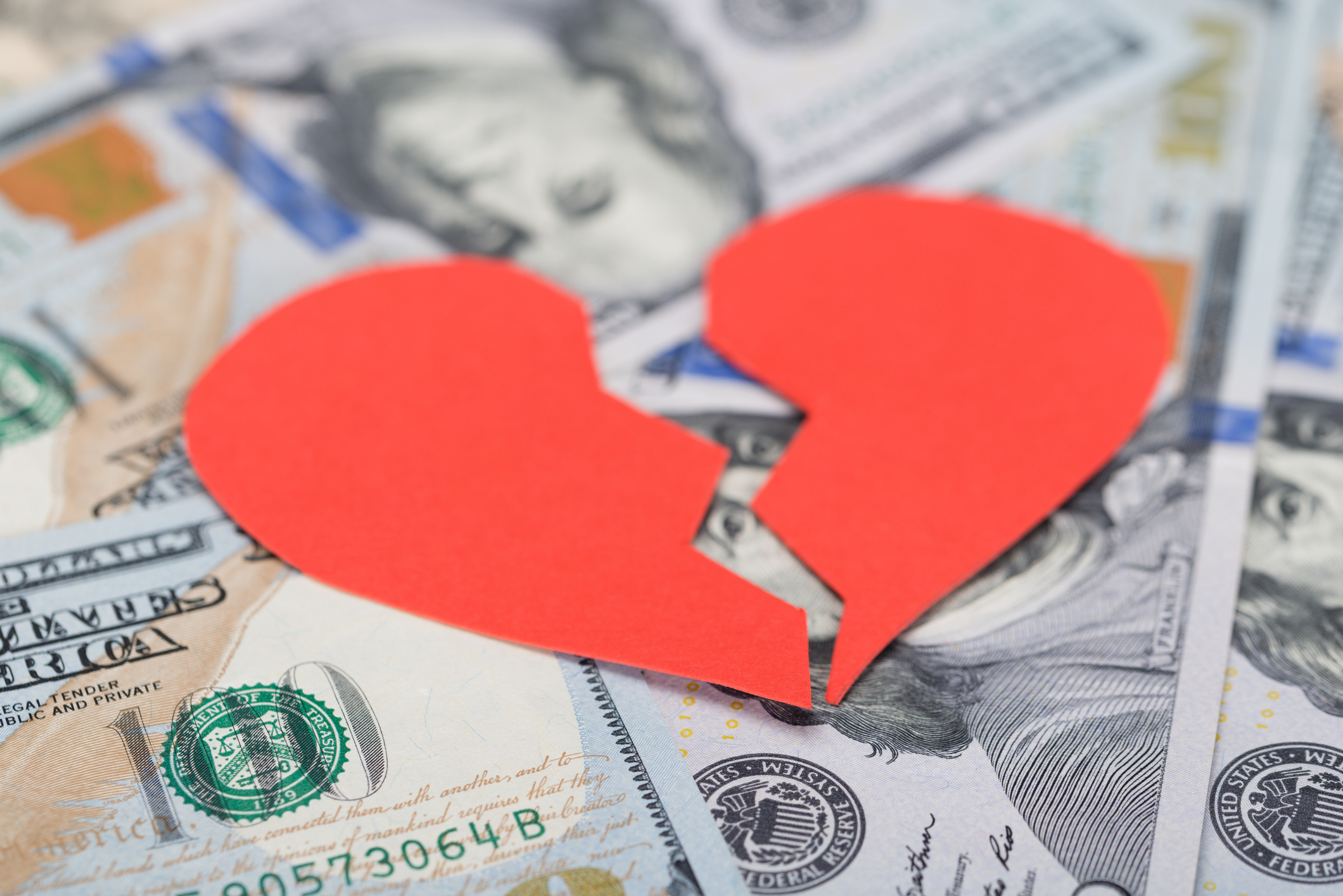 Broken heart on top of dollar bills.