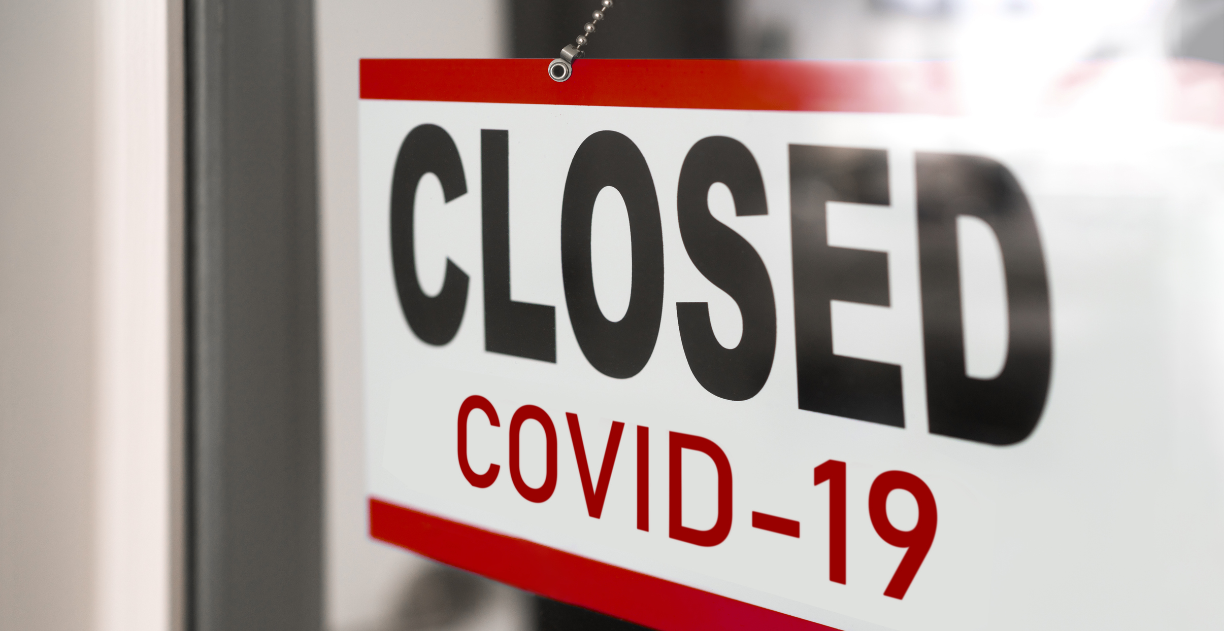 A sign reading "CLOSED COVID-19" in a glass window.