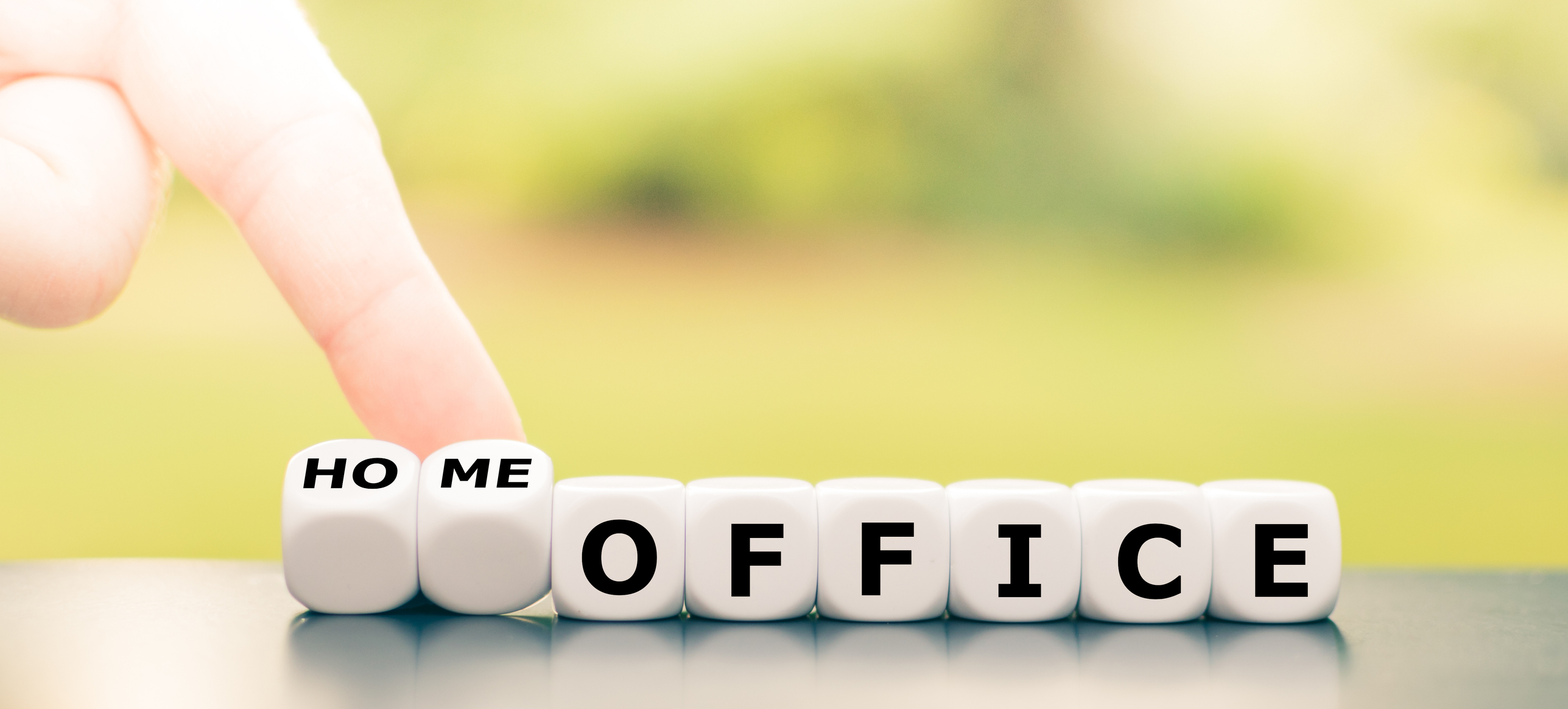 A person is flipping over some dice that spell the word home in front of the word office.