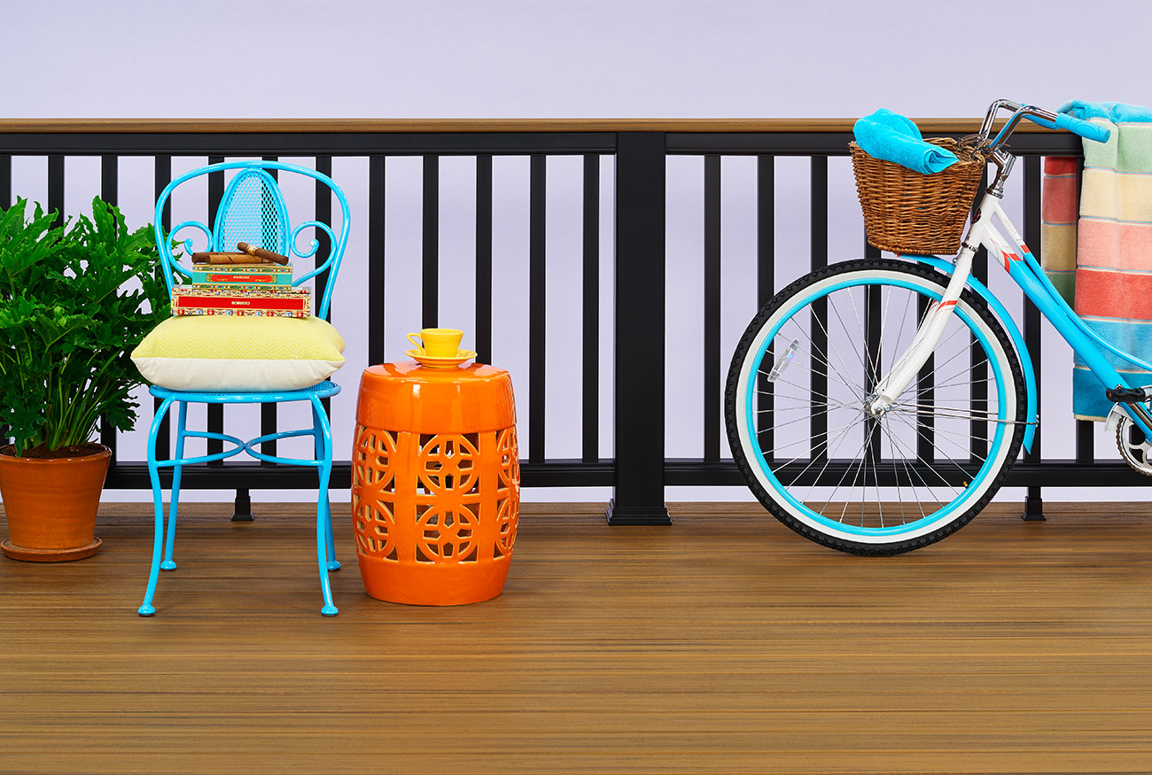 A Trex deck with various colorful objects including a bike, chair, and potted plant on top.
