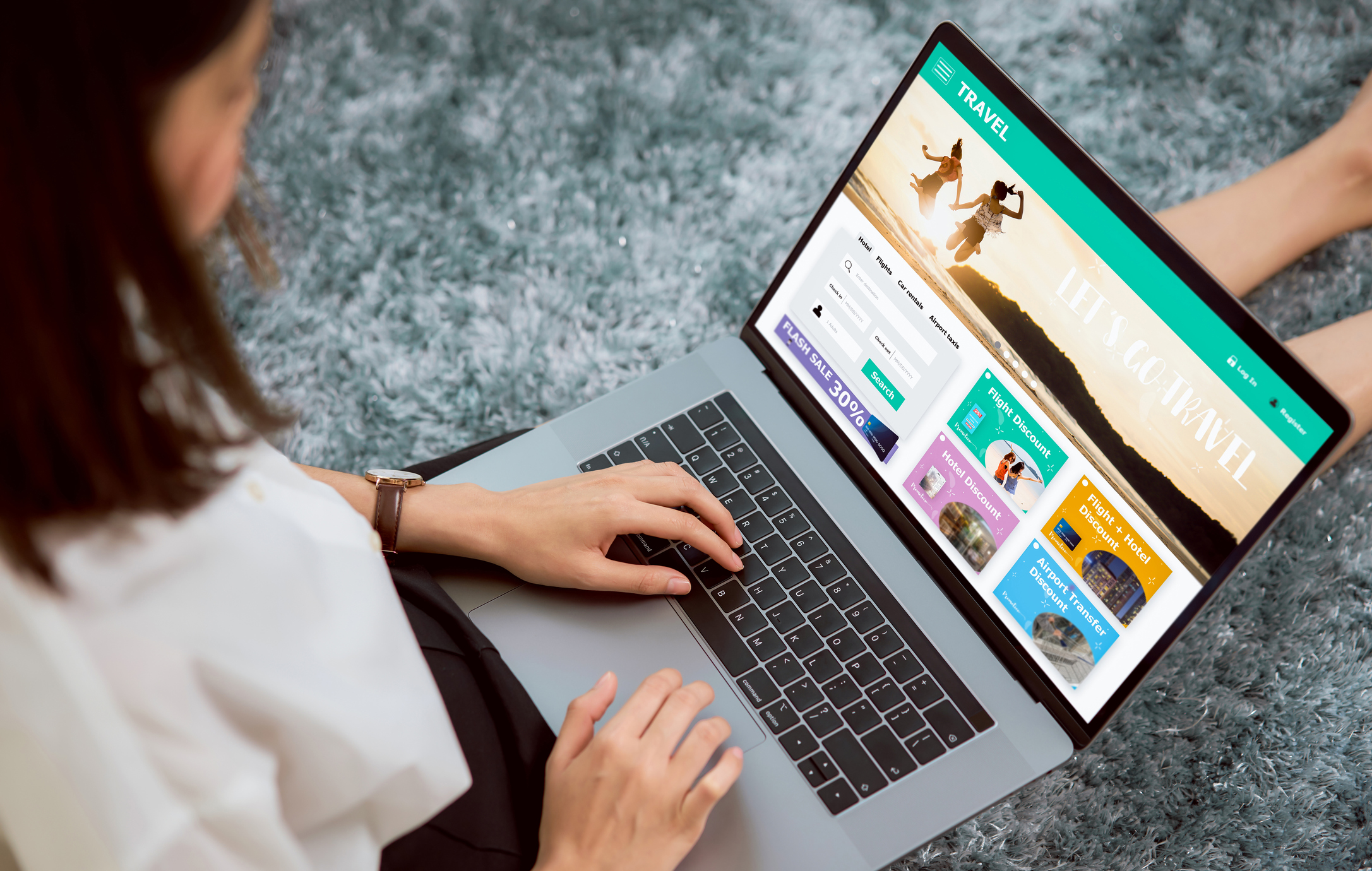 A woman looks up travel options on her laptop seen over the shoulder.