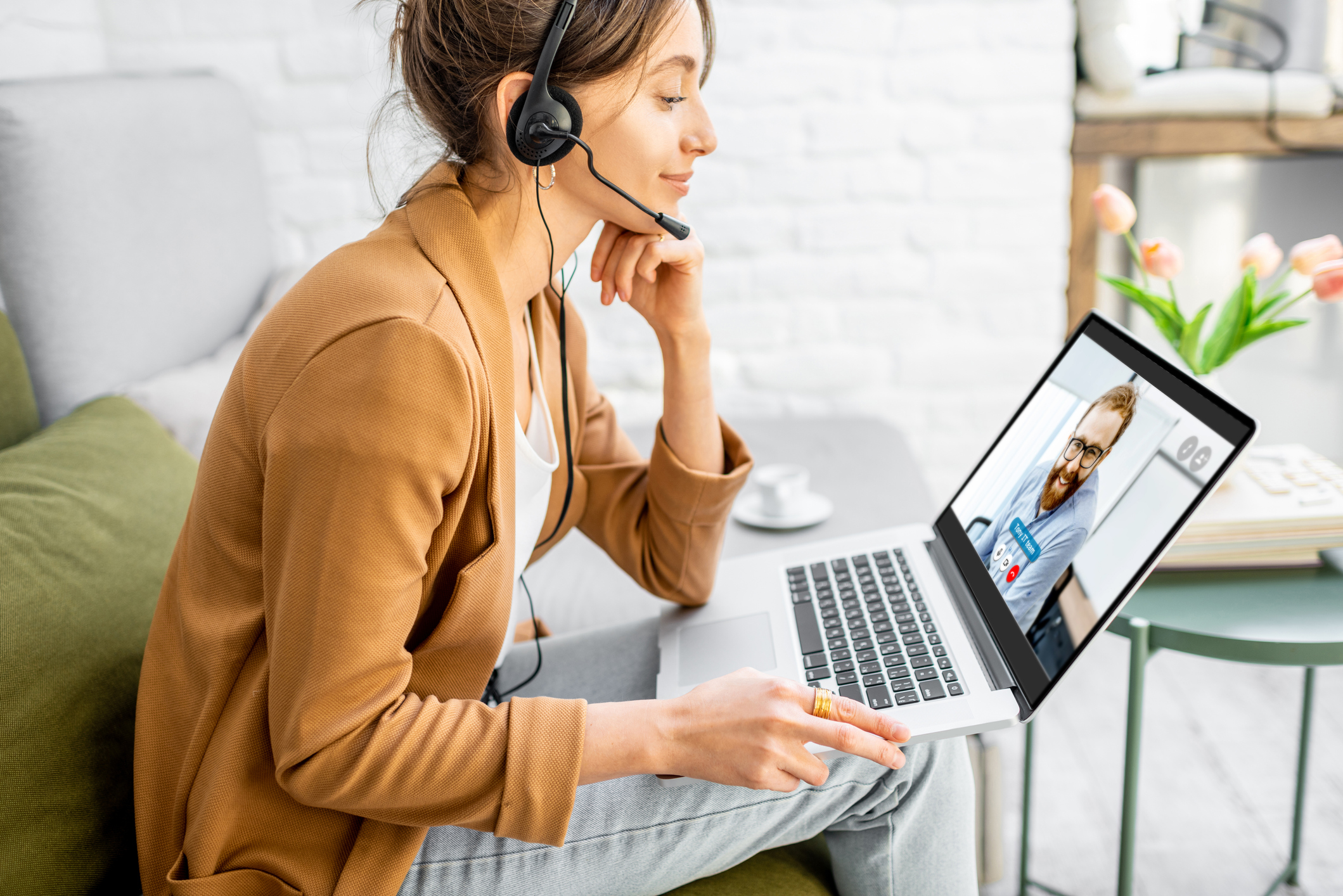 Woman working at home on a laptop while wearing a headset.
