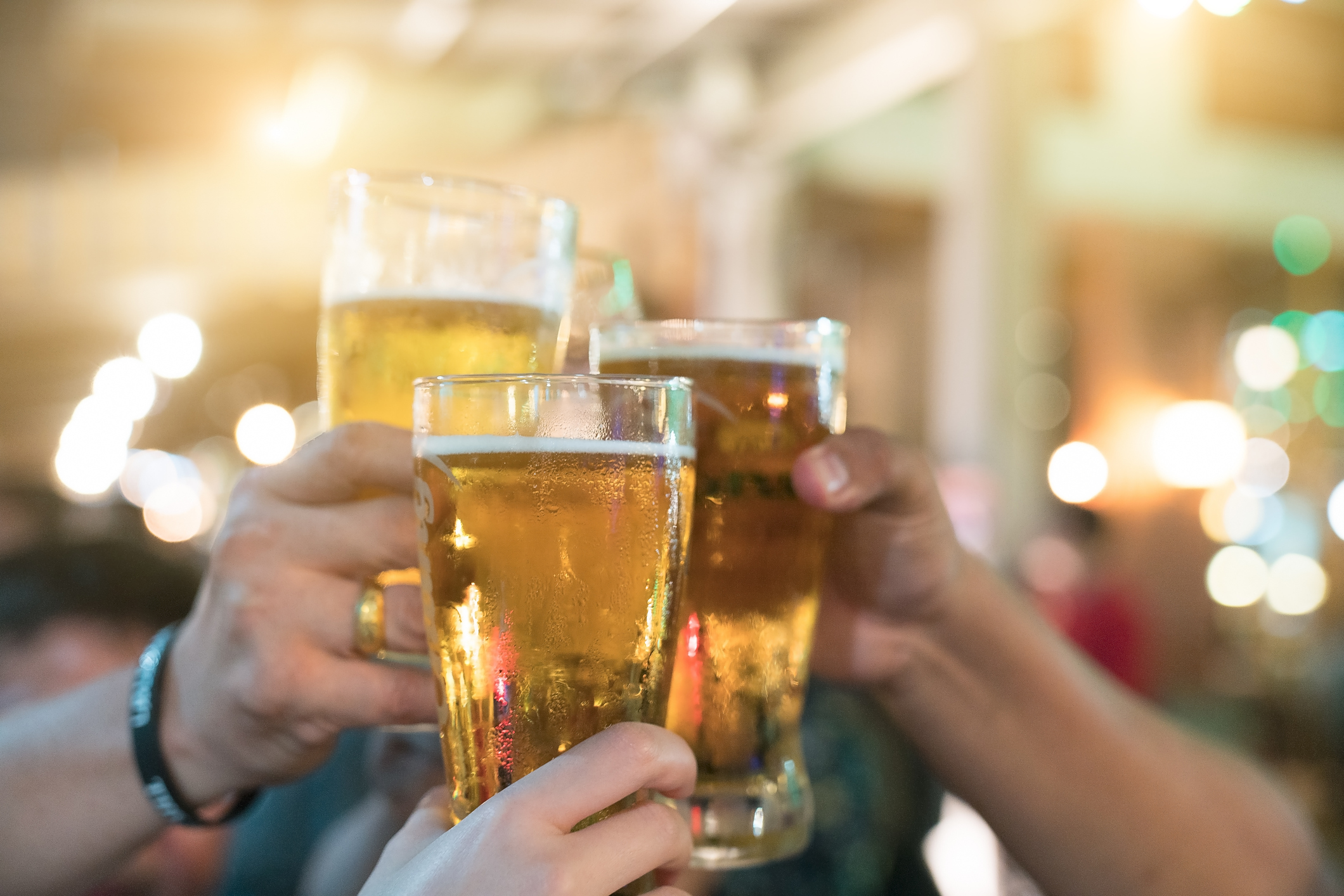 Three beer drinker clink their glasses.