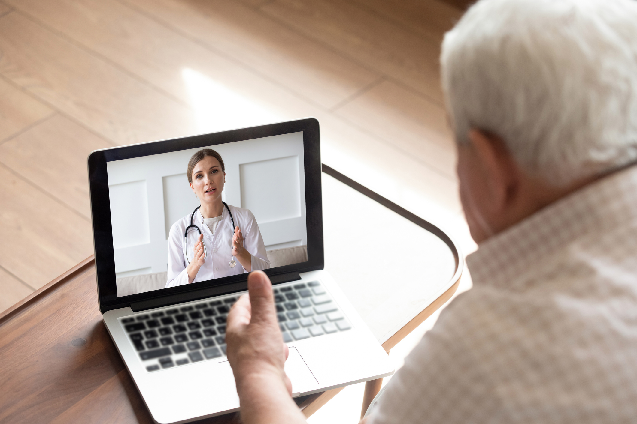 An older person looking a physician on a laptop screen