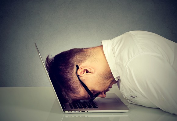 Man with head down on laptop keyboard.