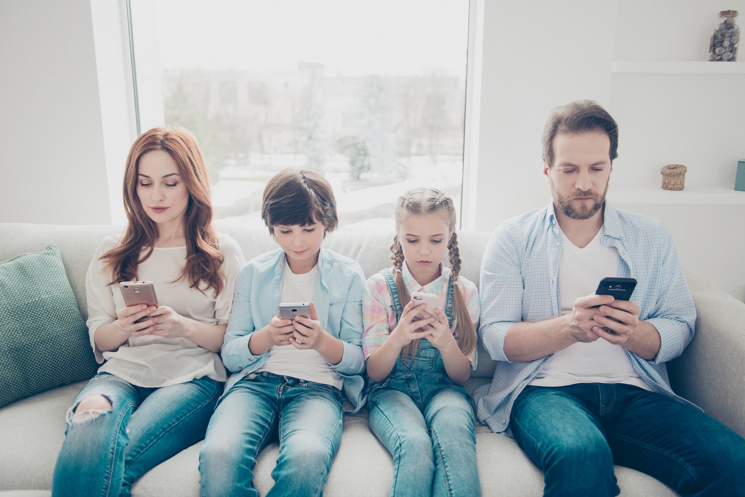 Family on the couch looking at their phones.