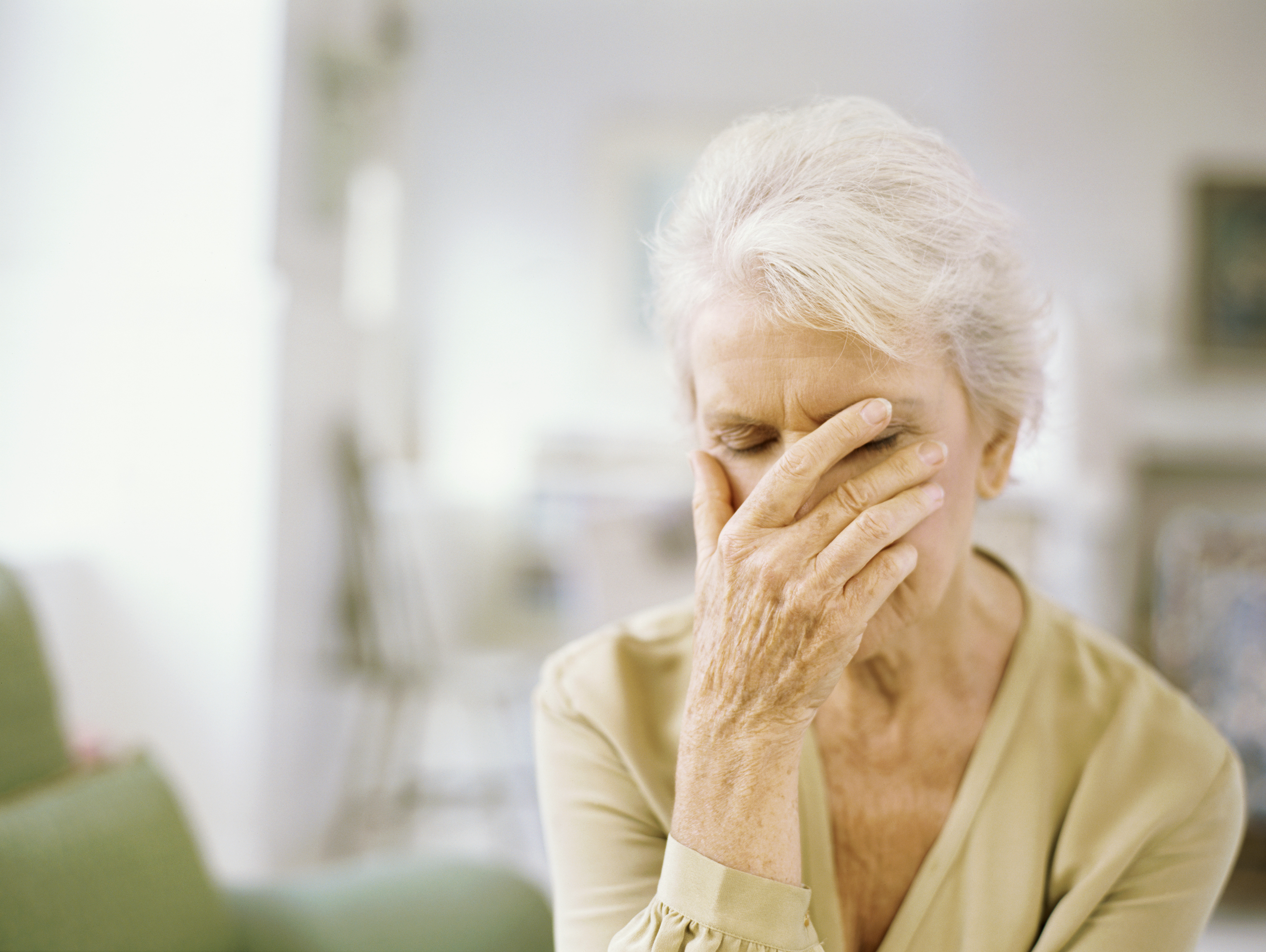 A senior woman buries her face in her palm out of frustration.