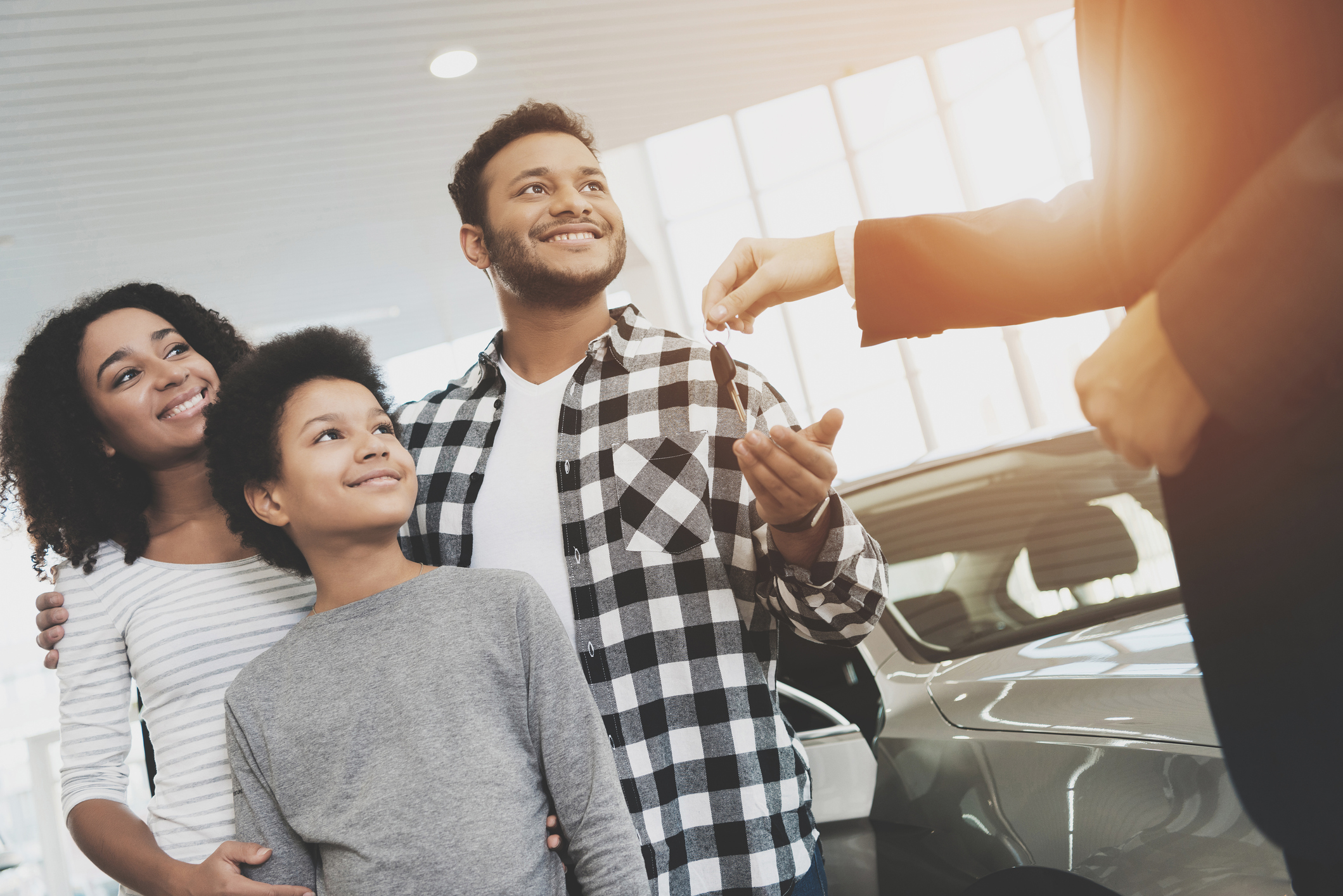 family being handed keys by car dealer in showroom