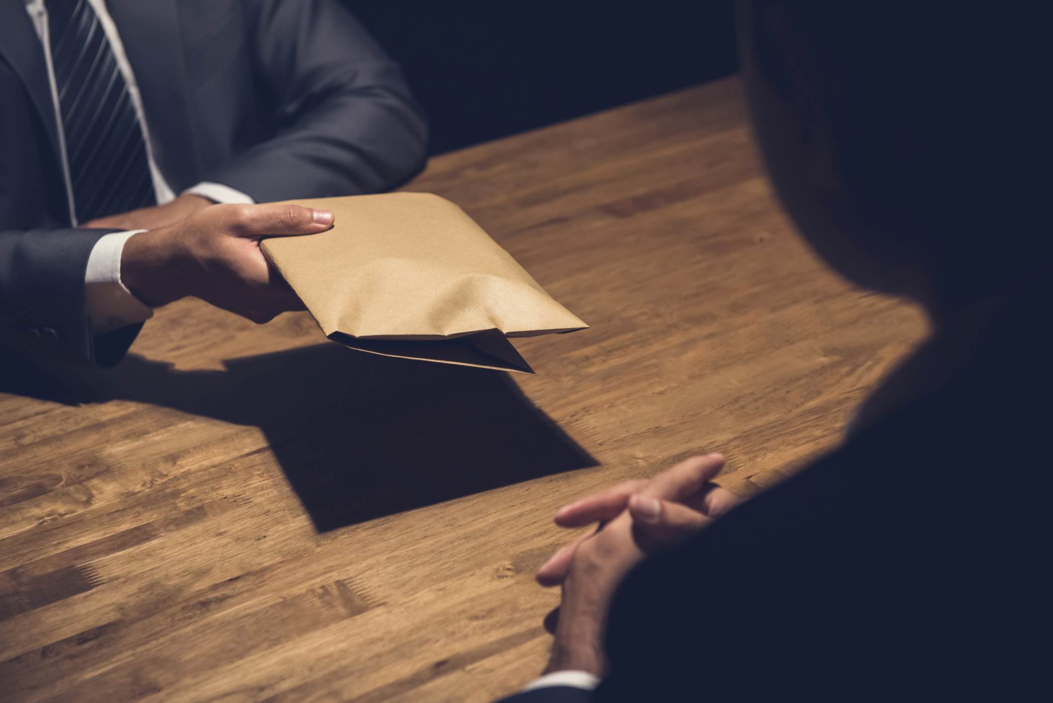 One businessman handing an envelope to another.