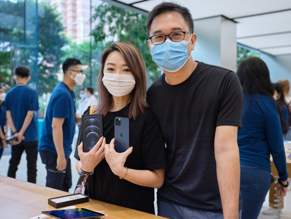 Customer holding an iPhone 12 Pro at launch in an Apple Store