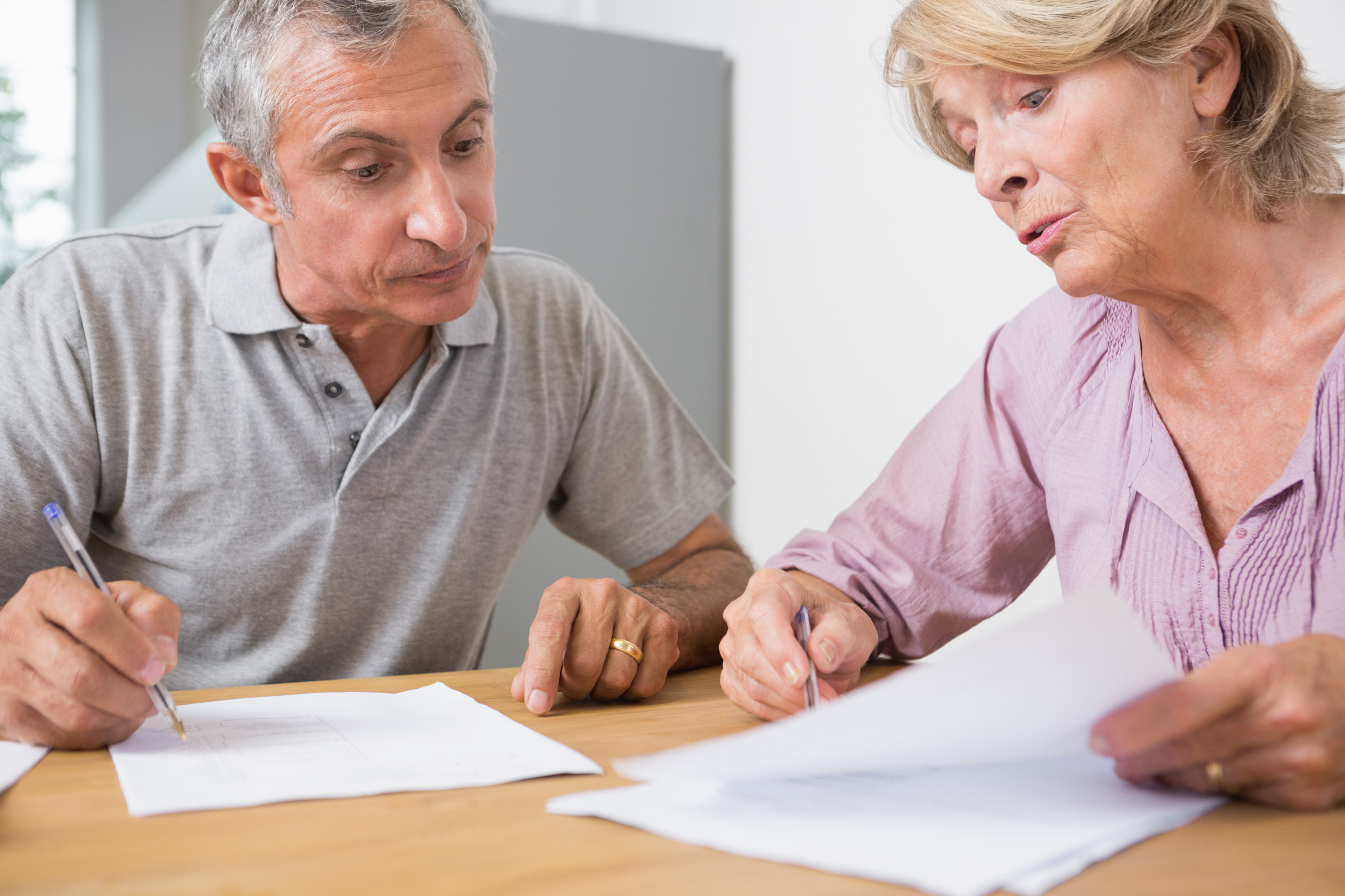 Older man and woman holding pens to documents