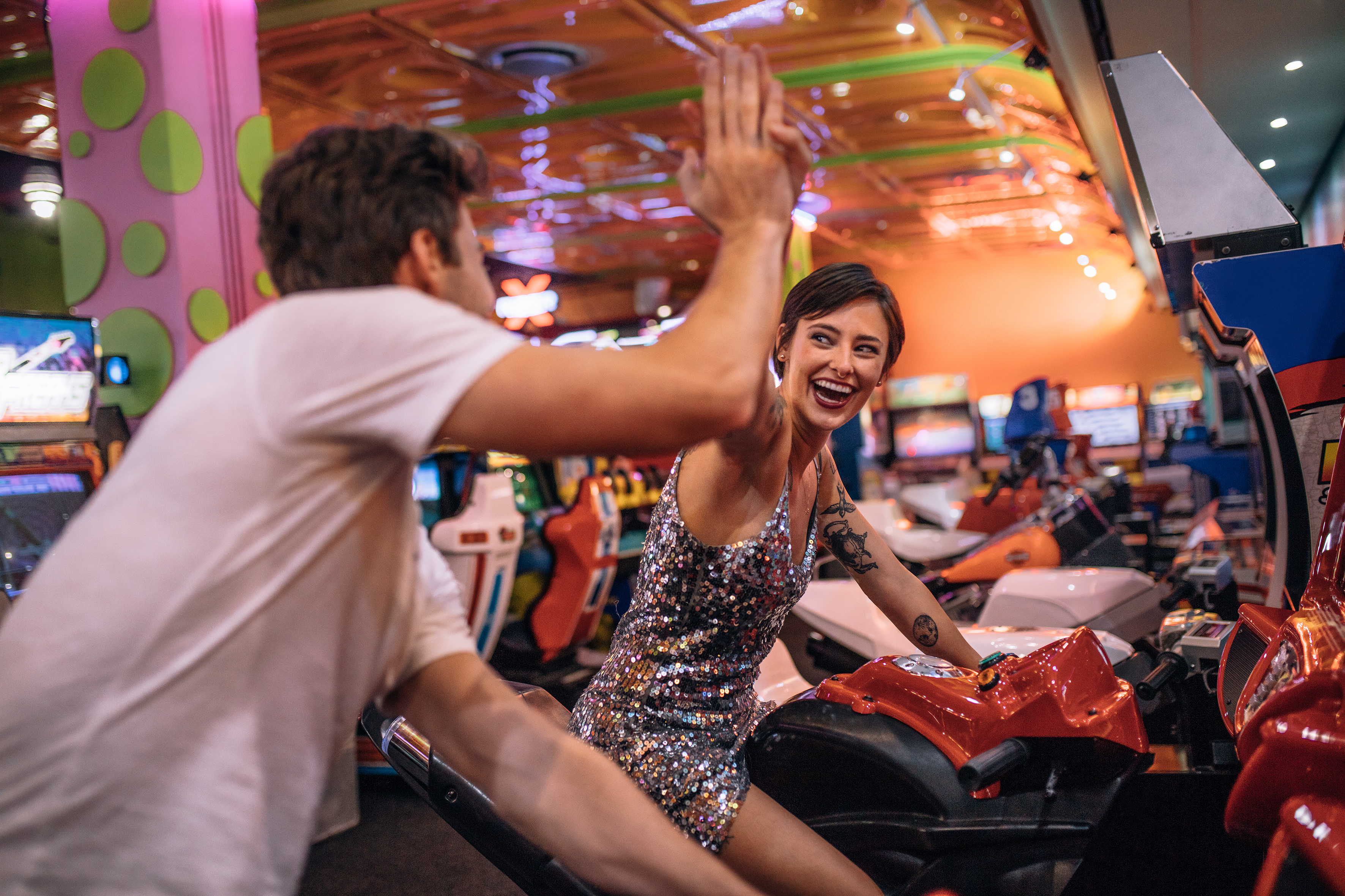 Man and woman high fiving at an arcade