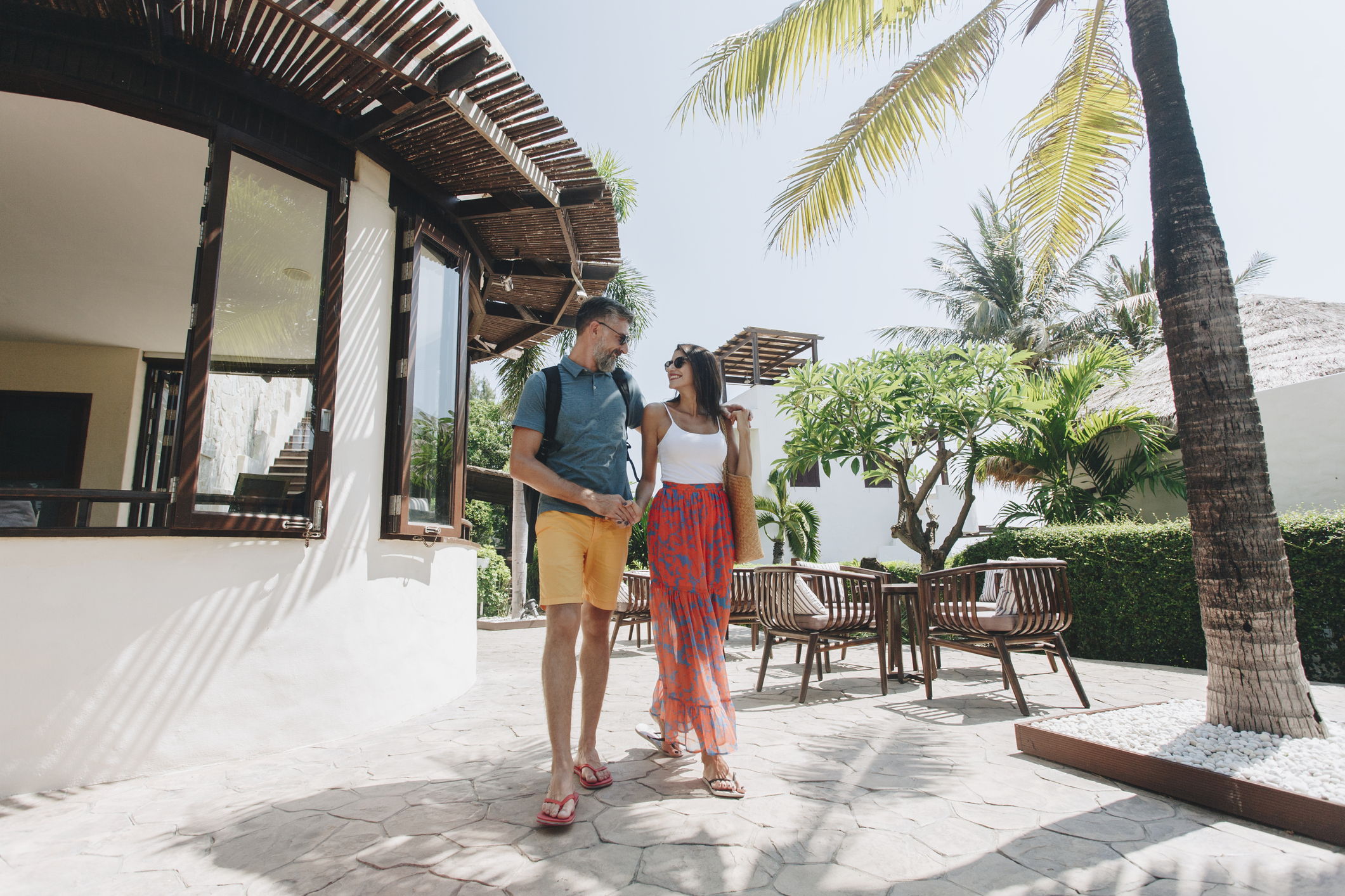 A man and a woman walking outside a tropical resort