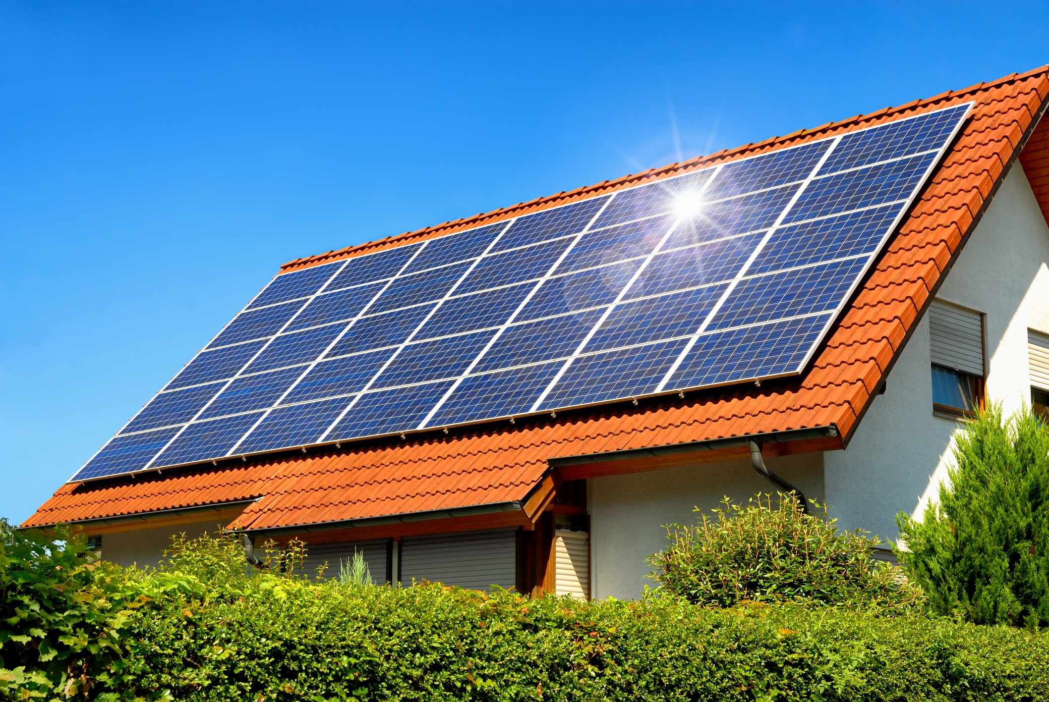 Home with large solar installation on the roof on a sunny day.