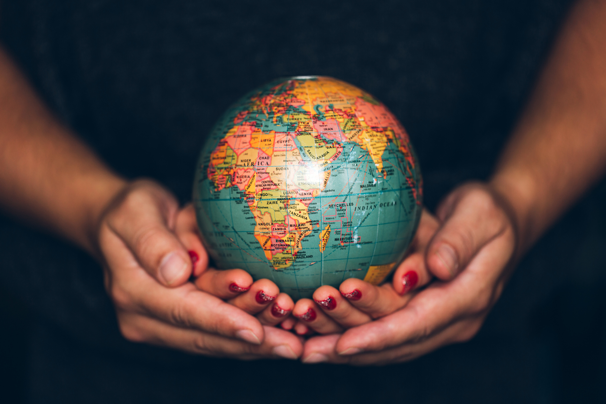 A man and a woman holding the Earth in their cupped hands.