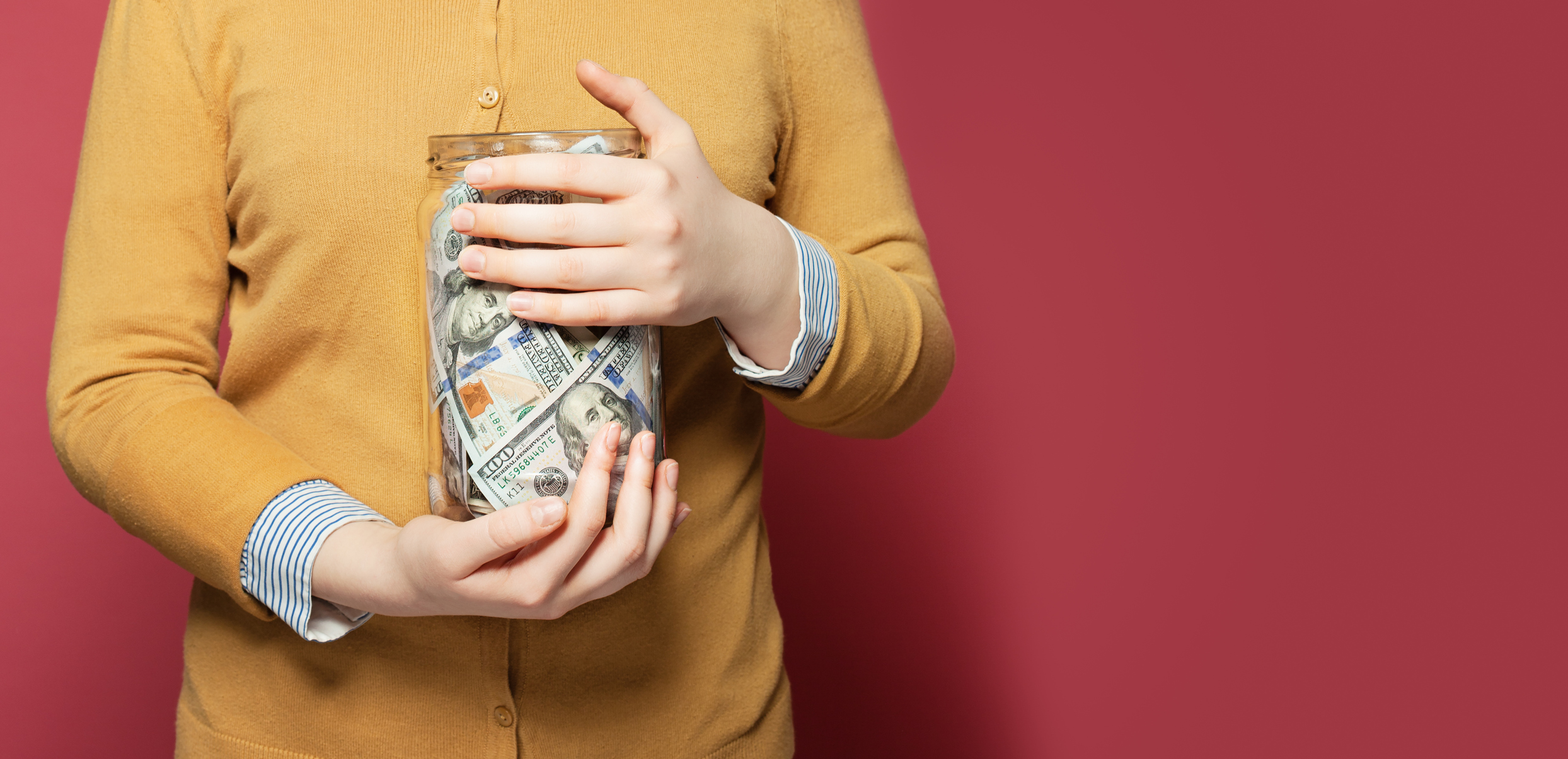 Person holding a jar full of money.