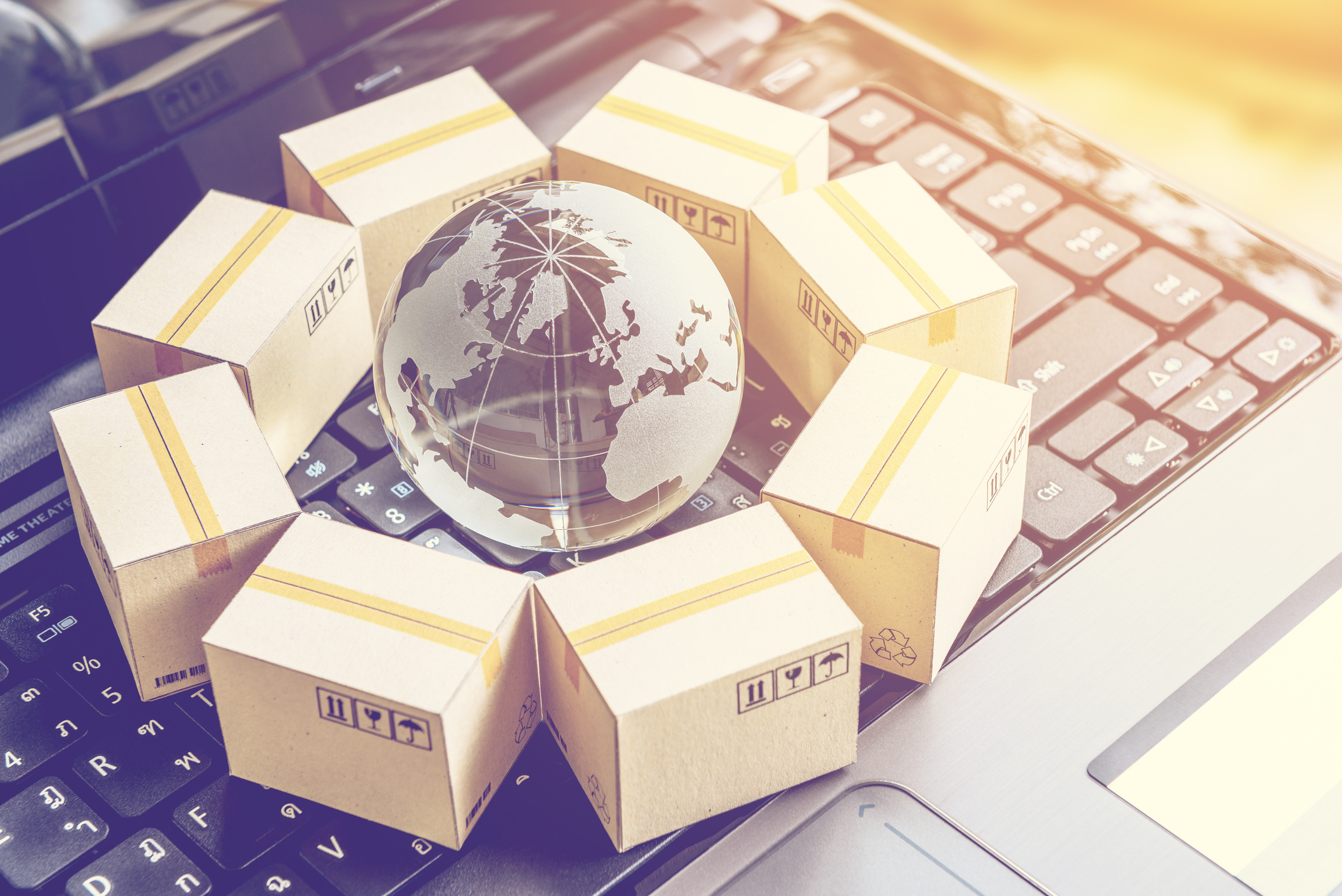 A globe and shipping boxes sitting on a laptop keyboard.