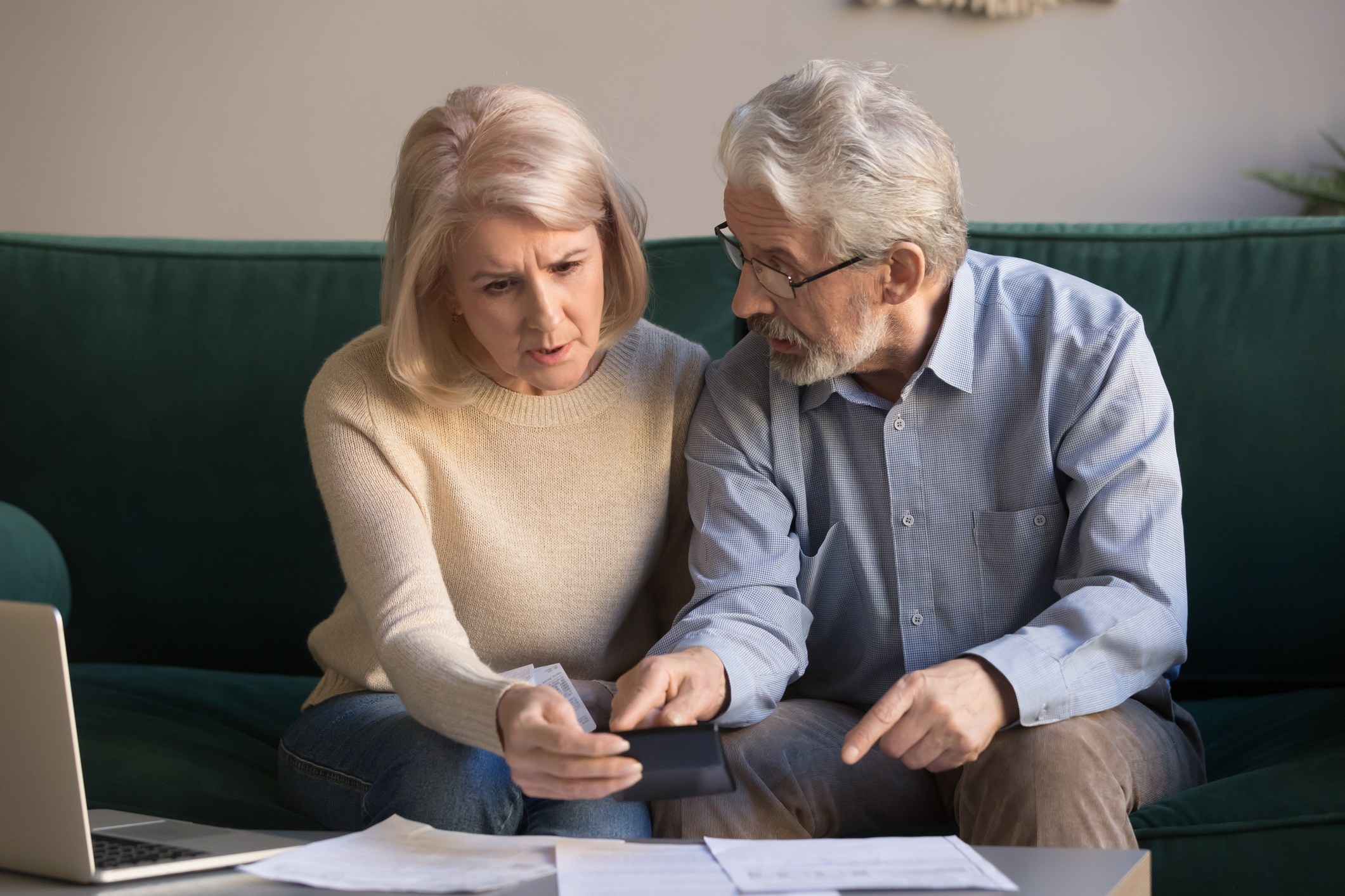 Older man and woman on couch with laptop and documents in front of them