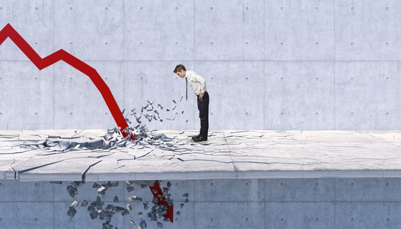 A businessman watches a red charting arrow crash down through the floor at his feet.