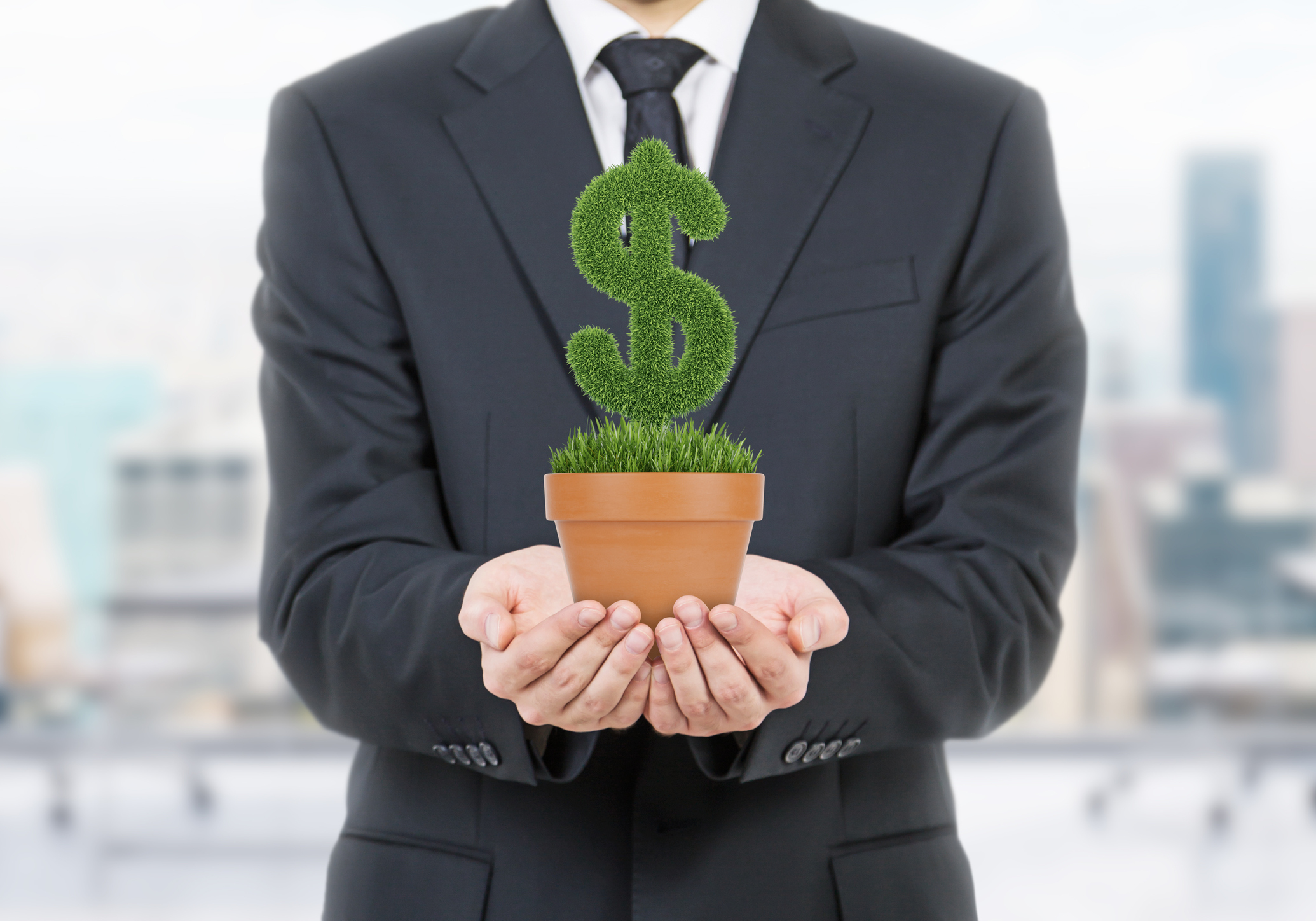 A businessman in a suit holding up a potted plant in the shape of a dollar sign.