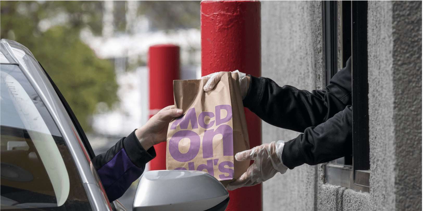 Customer in a car picking up an order at a McDonald's drive-thru window