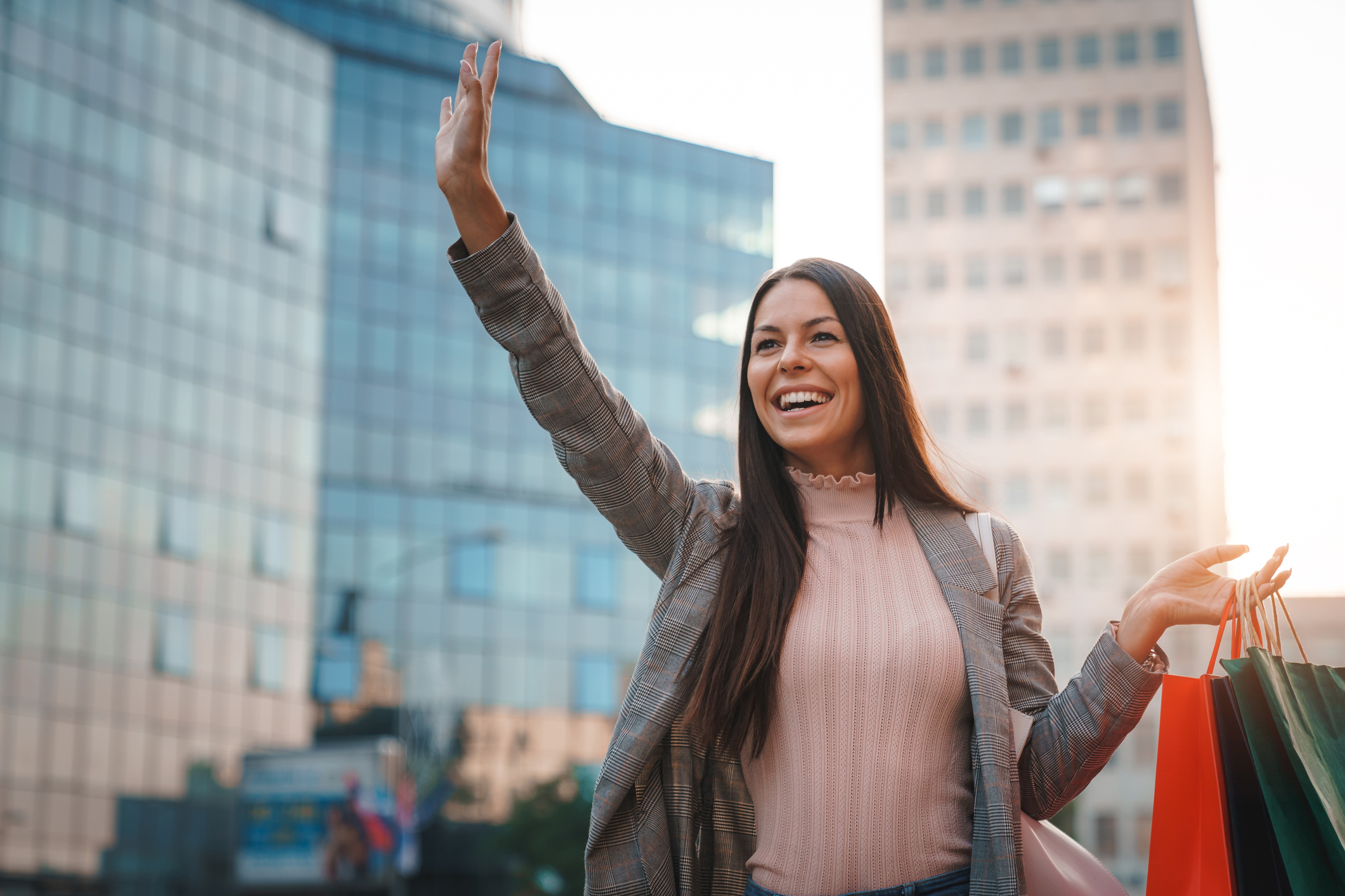 A young woman with her hand in the air hailing down a ride.