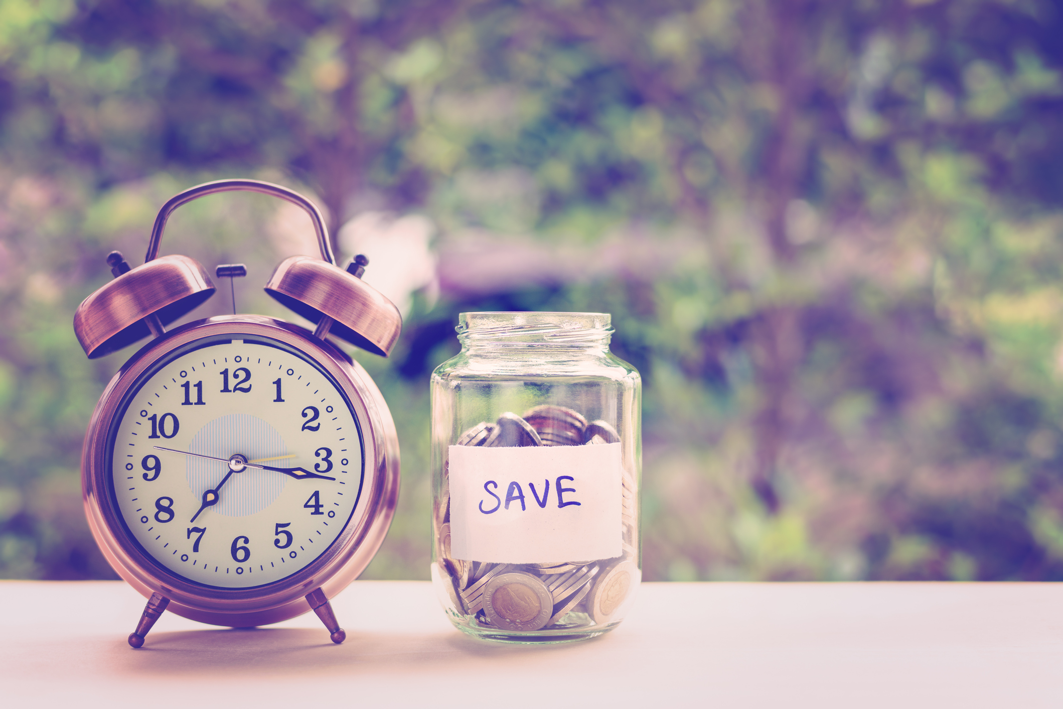Alarm clock next to a savings jar.
