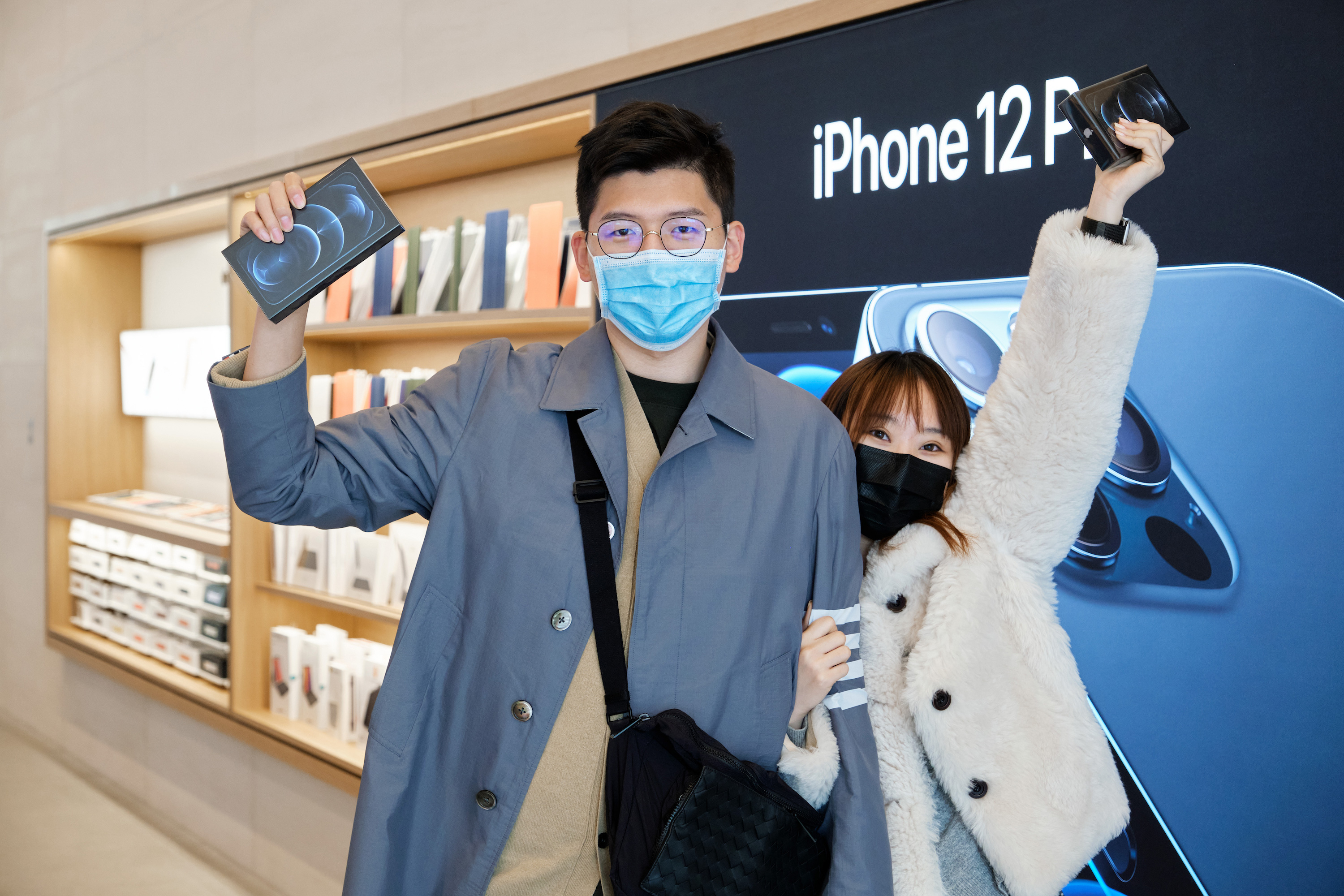 Customers holding up boxed iPhones at the Apple Store Sanlitun