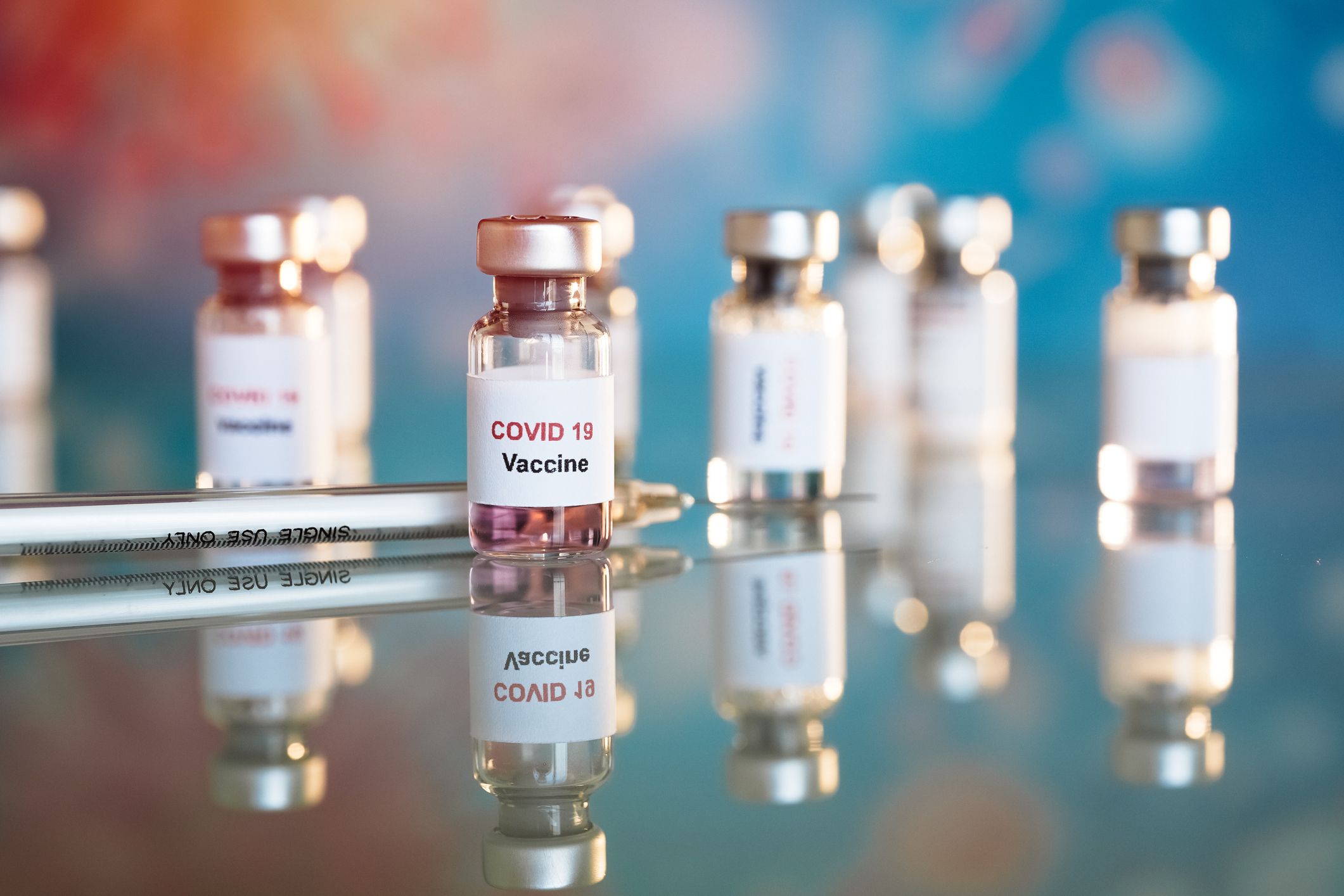 Syringe and several vials labeled COVID-19 Vaccine.