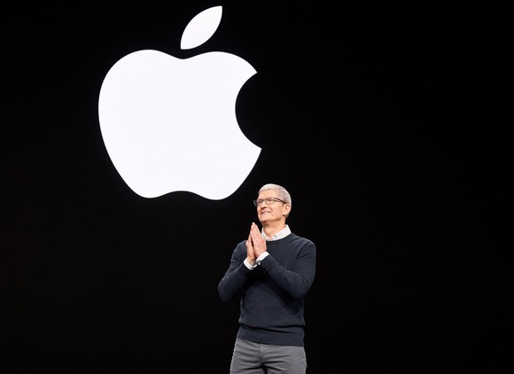 Apple CEO Tim Cook on stage with the Apple logo on the screen behind him.