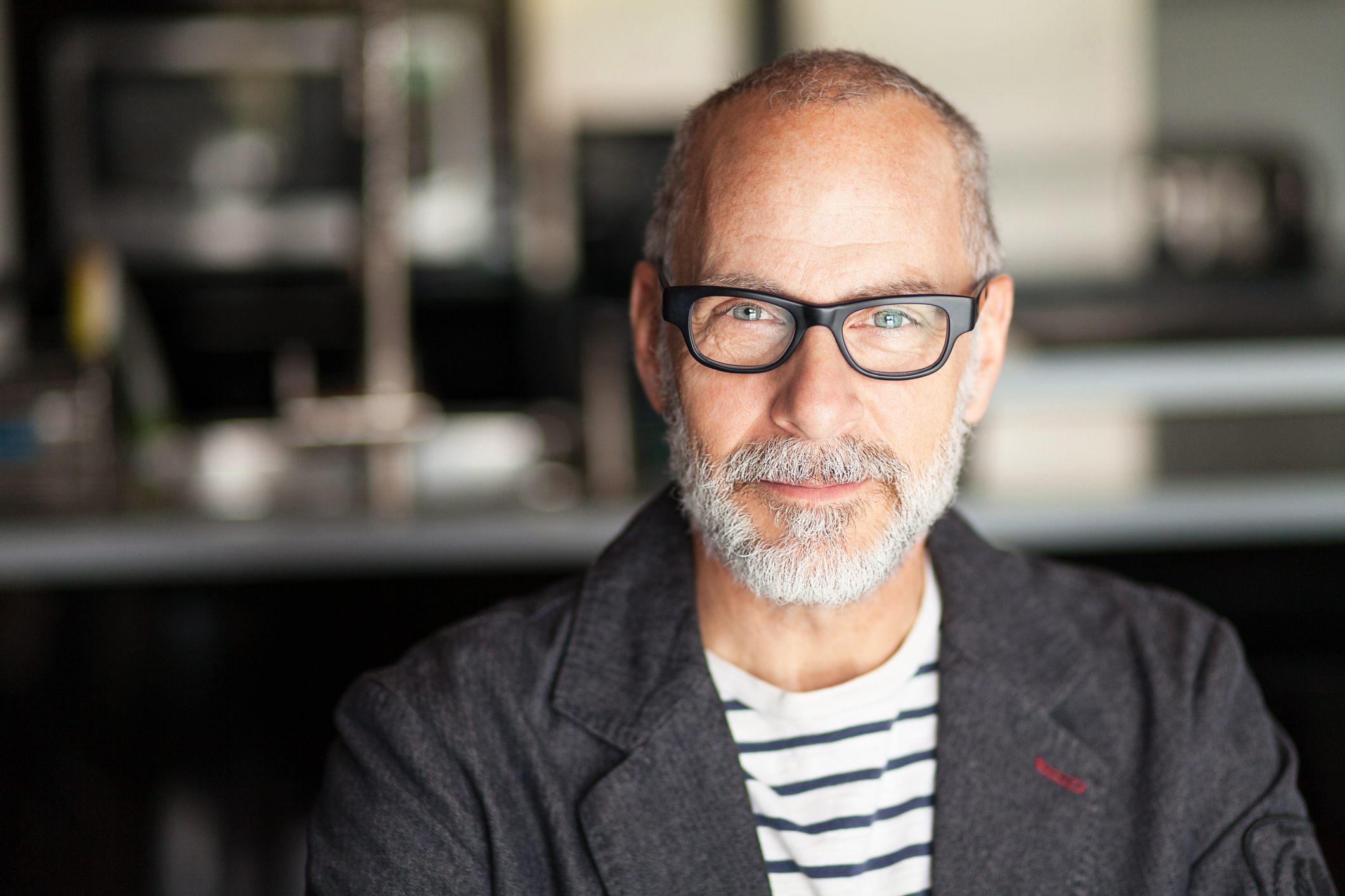 Smiling older person with glasses and beard.