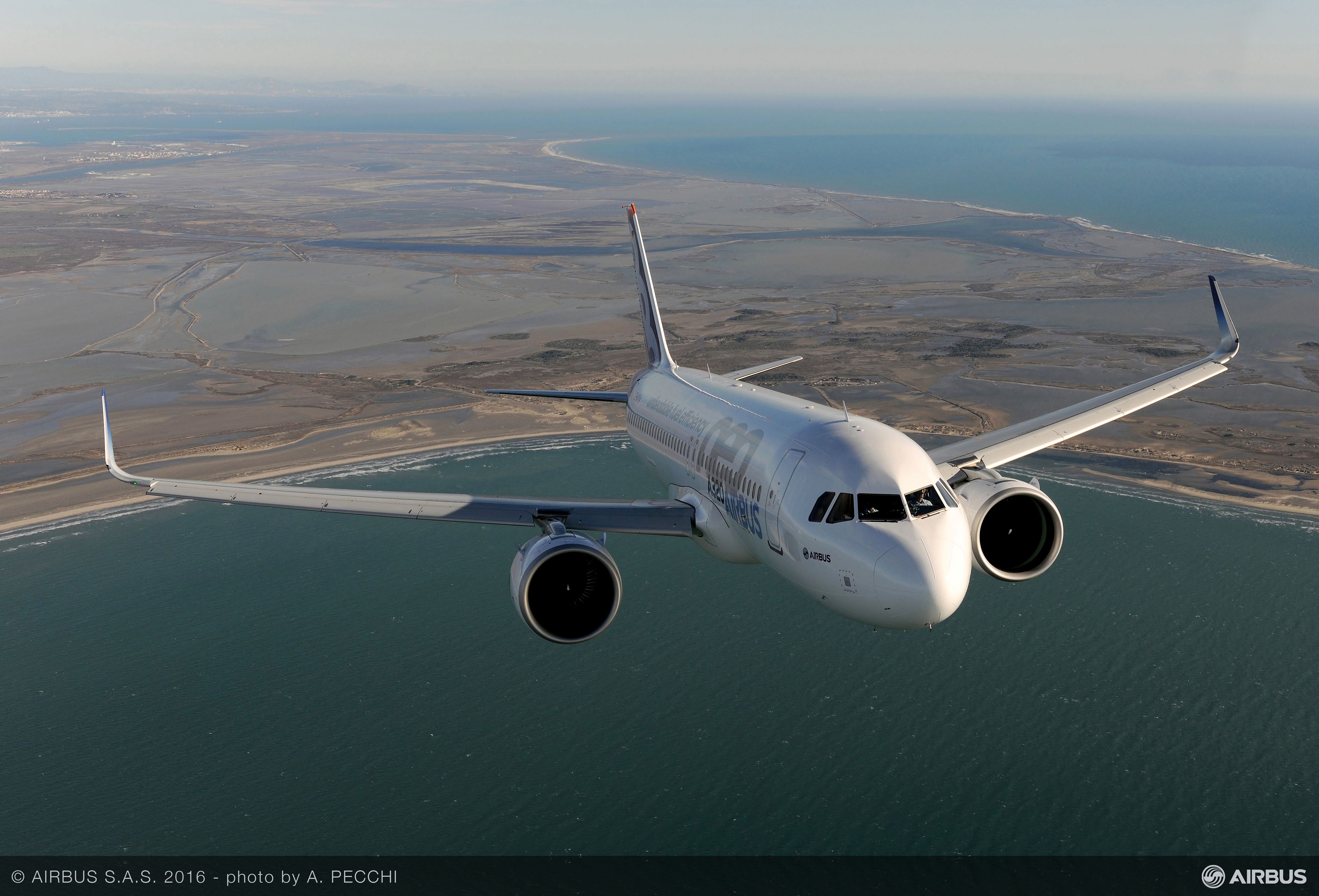 An Airbus A320neo flying over water.