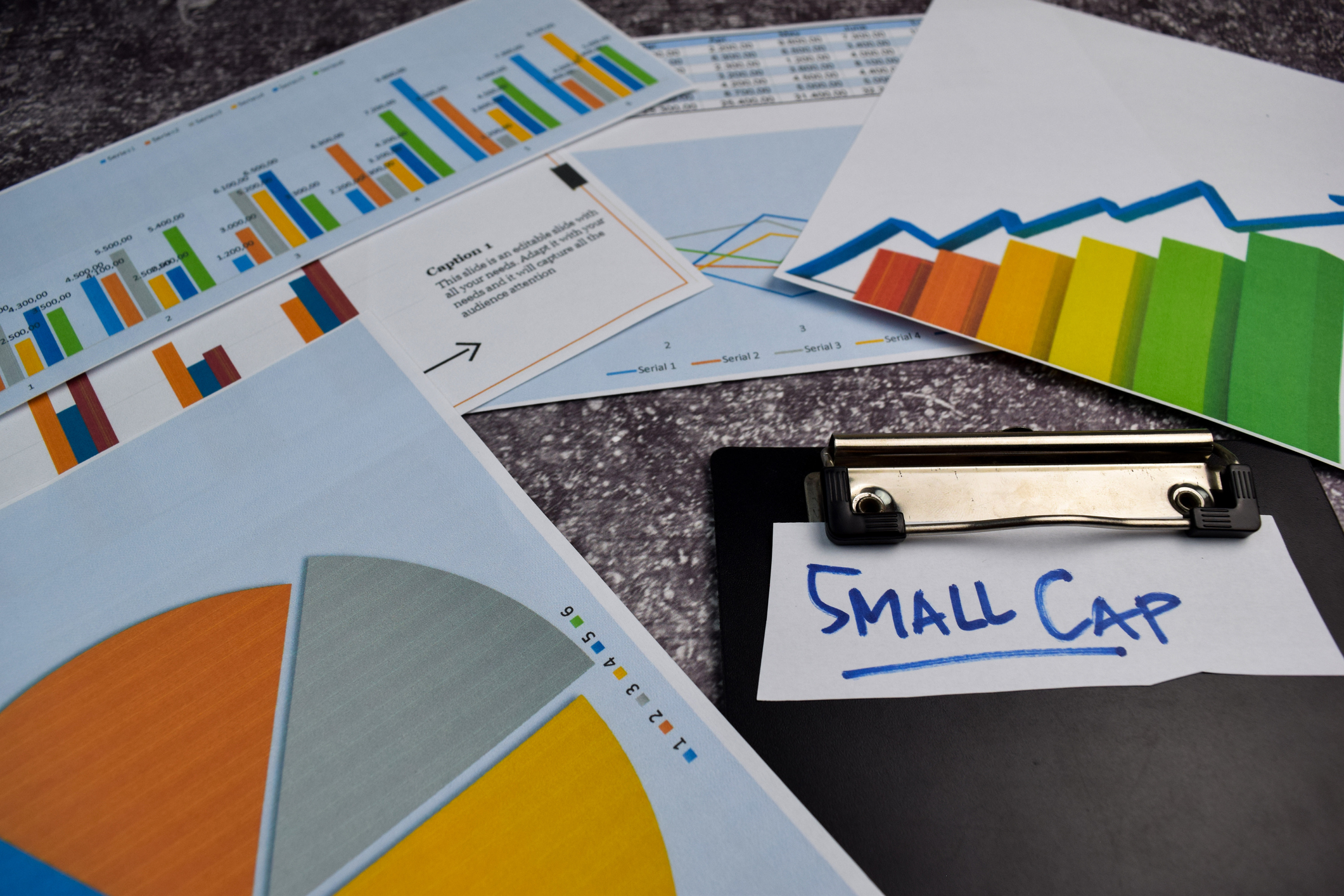 A clipboard with a note saying "small cap" surrounded by charts.
