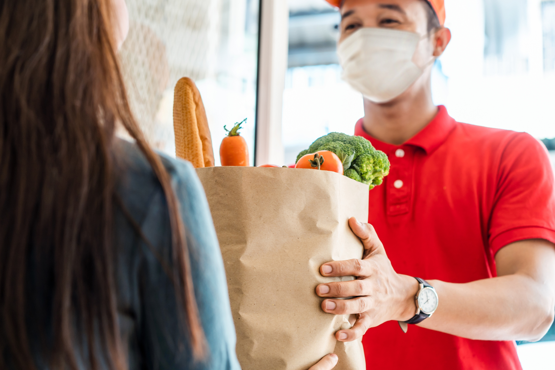 Delivery person giving a customer a bag of groceries.