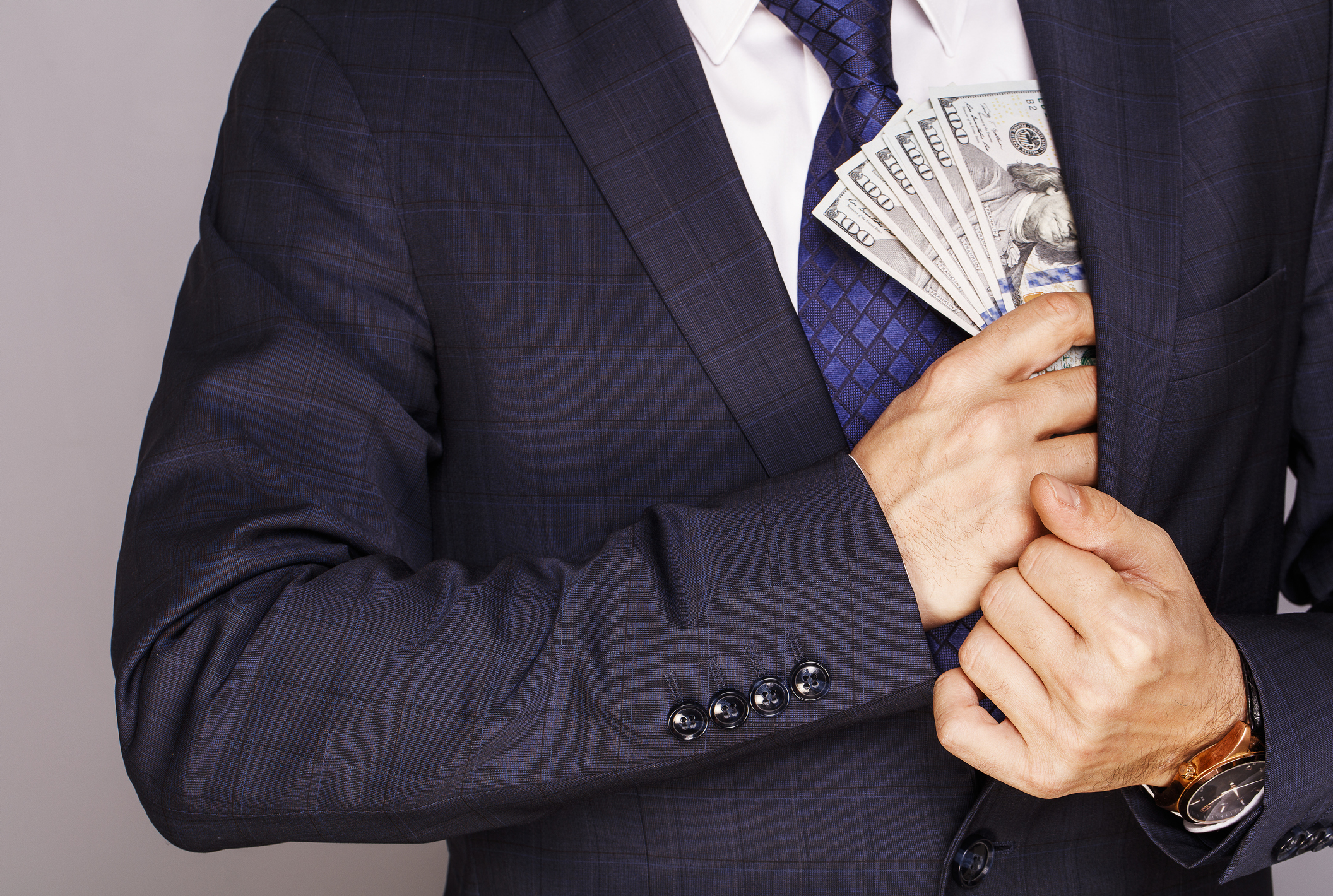 Getty - man putting cash money in pocket rich wealthy dividends