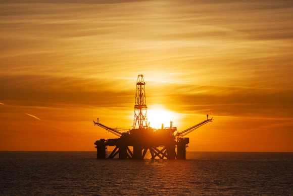An offshore drilling rig with the sun setting in the background
