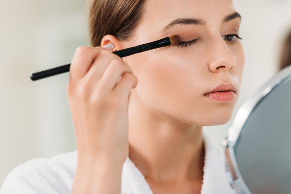 A woman applies makeup.