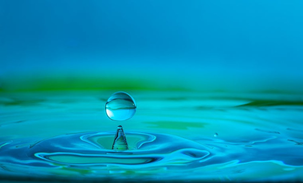 Water droplet falling into a body of water and causing ripples.