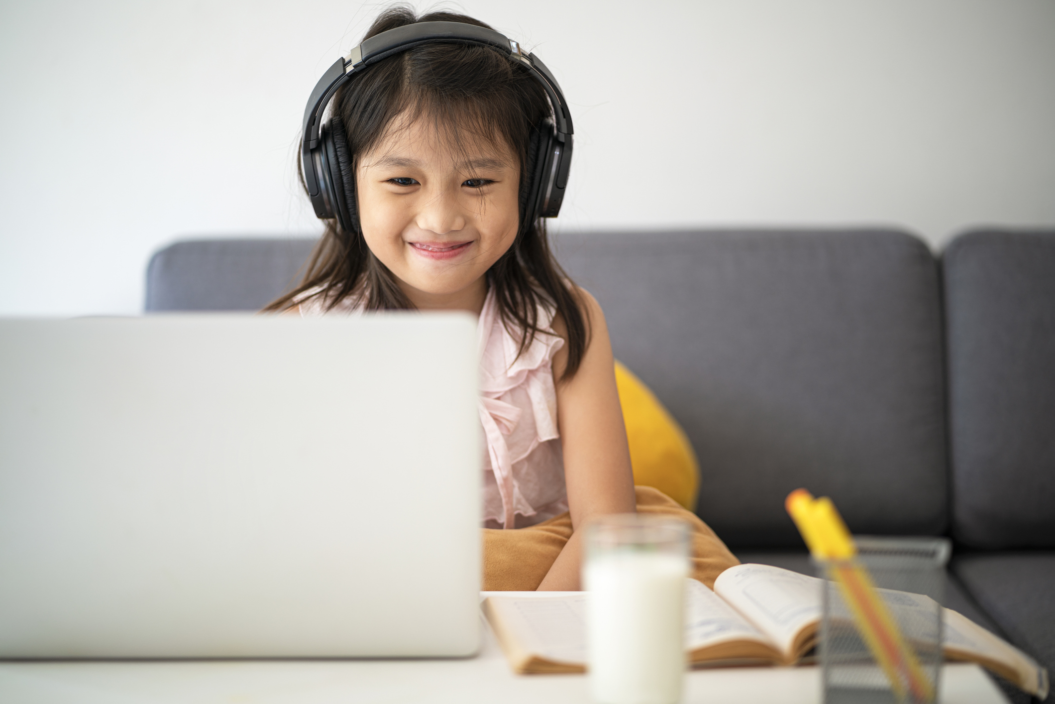 A young girl takes an online class on a laptop.