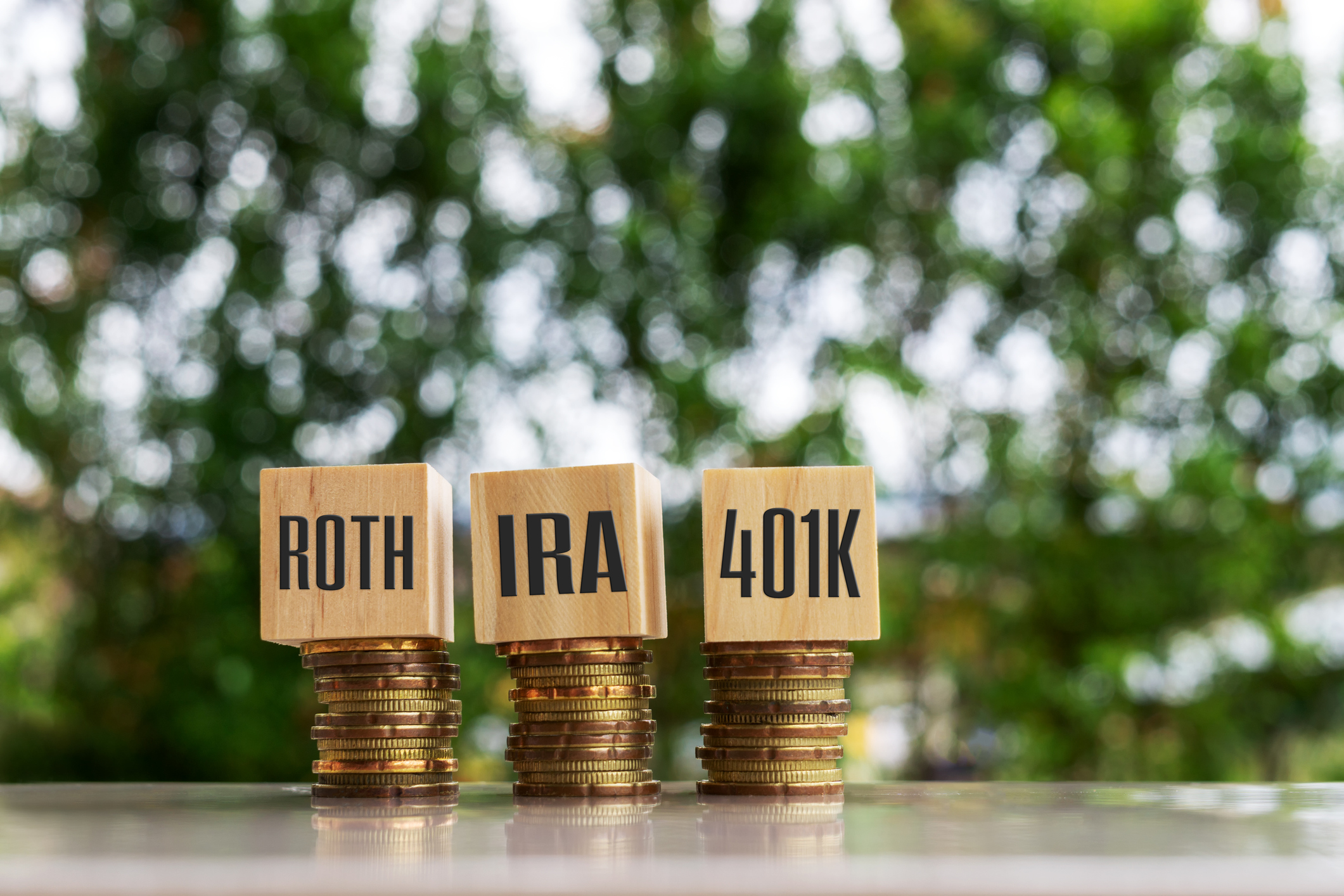 Stacks of coins with blocks on top that say Roth, IRA, and 401k