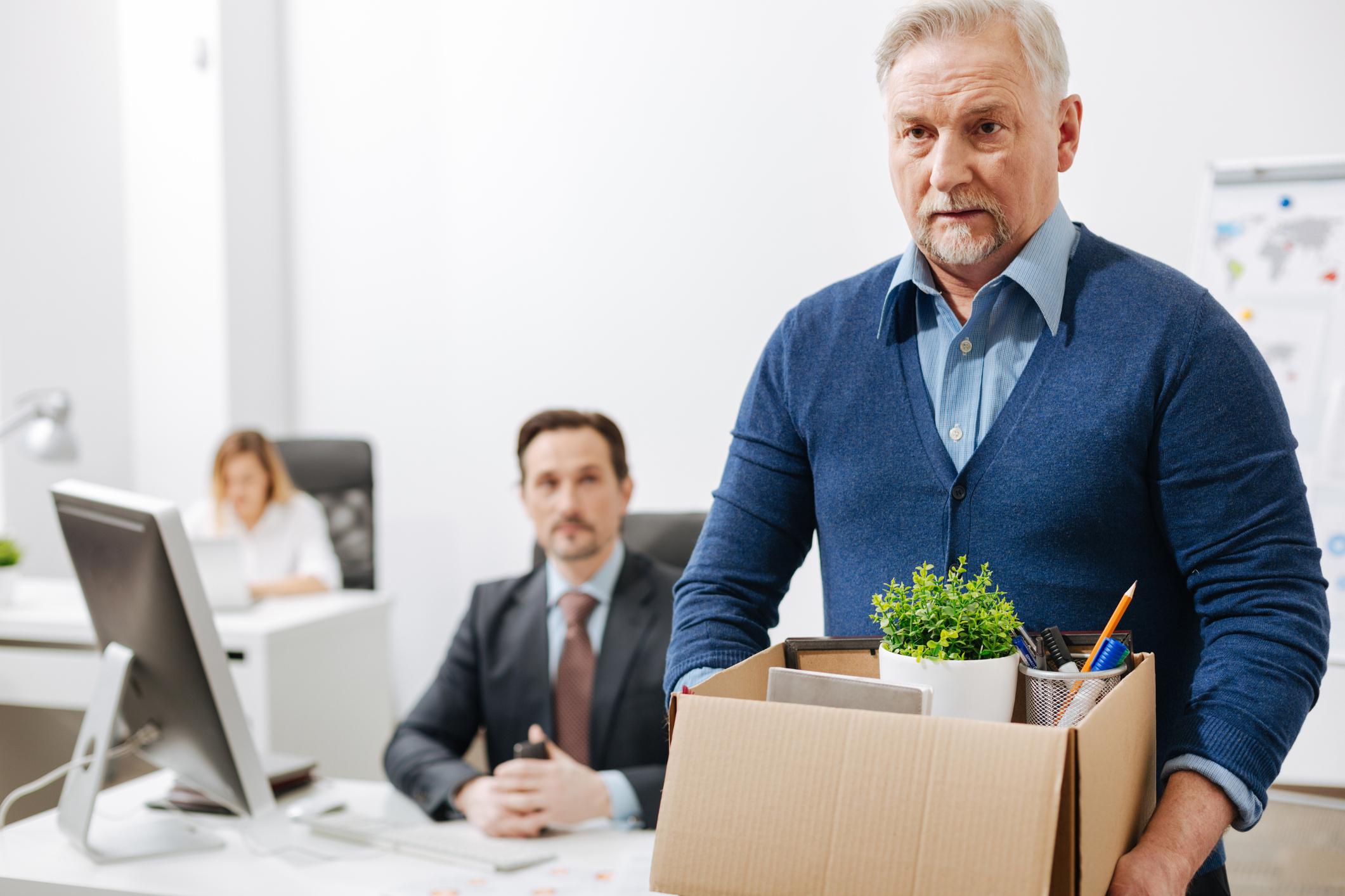 Senior man leaving office with a box of his belongings.