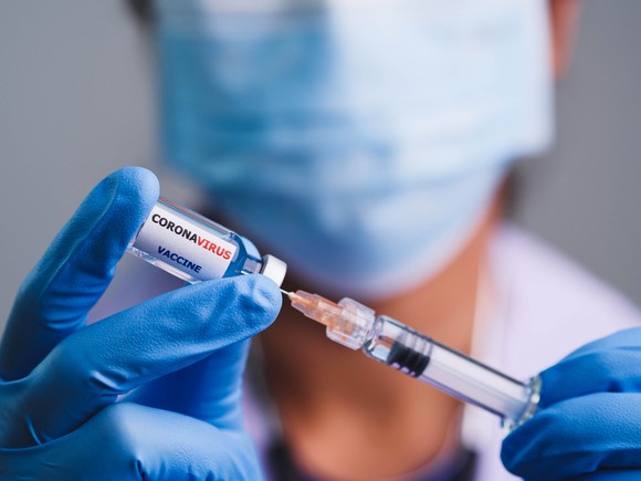 A masked doctor draws up a dose of coronavirus vaccine.