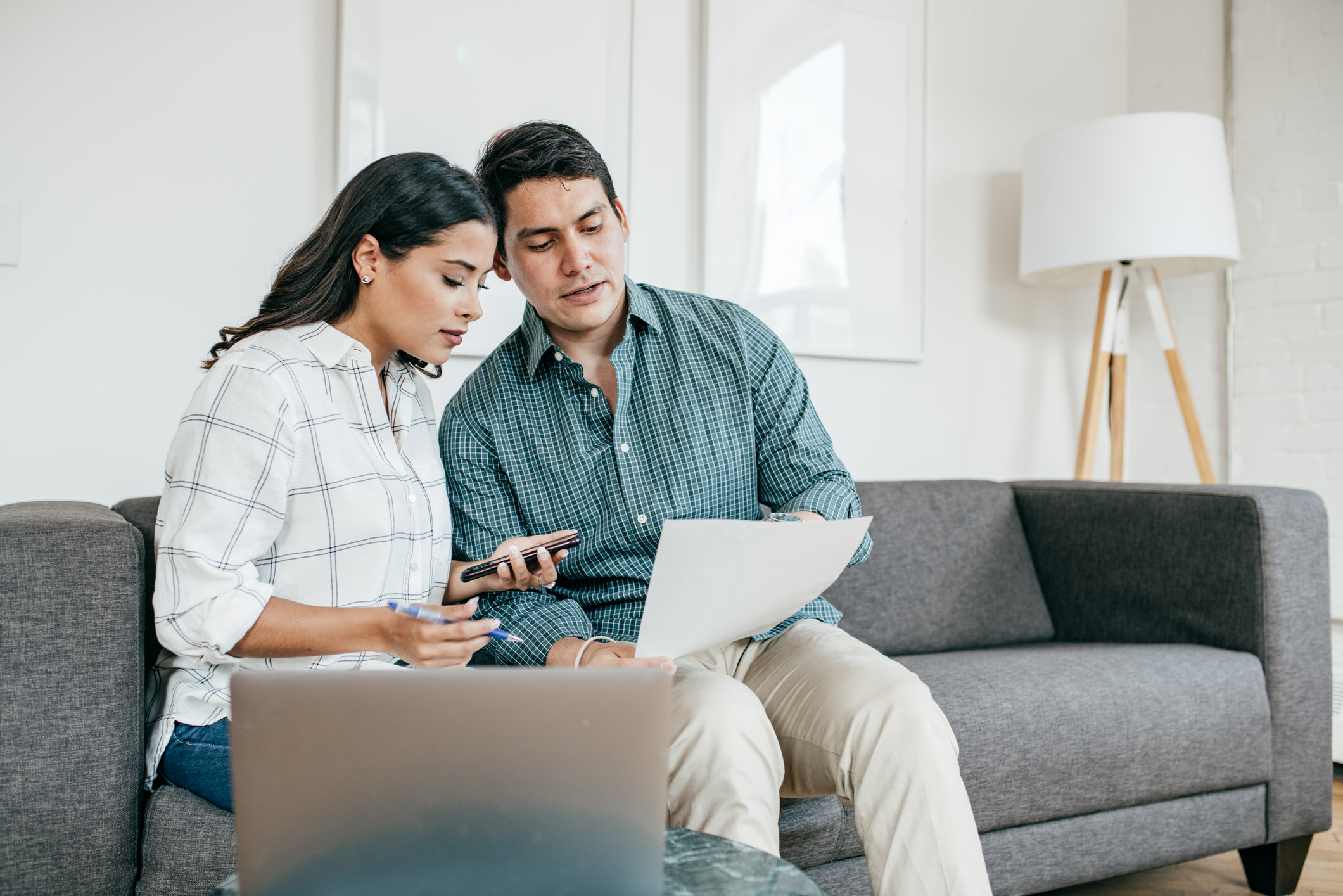 Man and woman sitting on a couch looking at documents