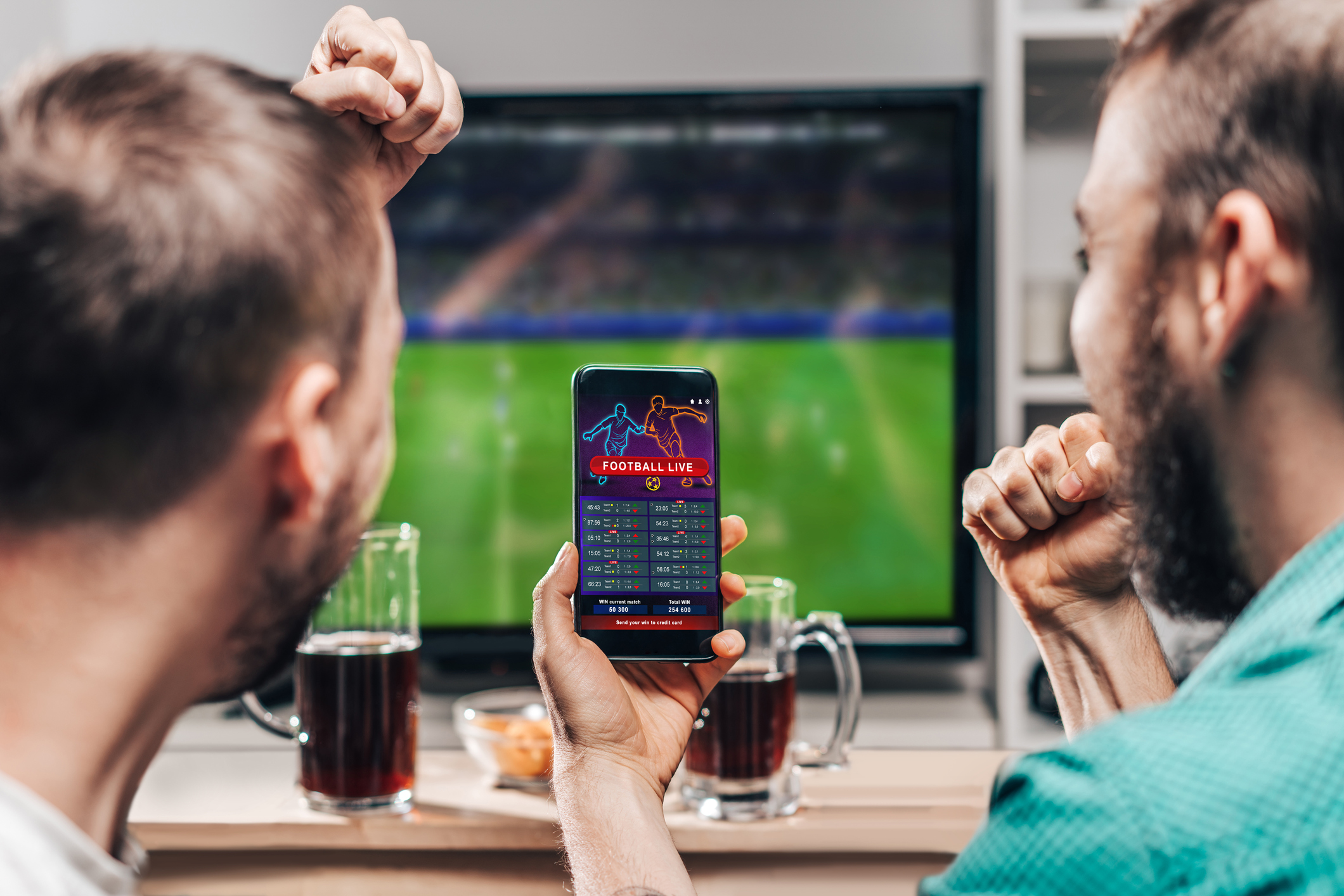 Two people betting on live sports on a mobile device.