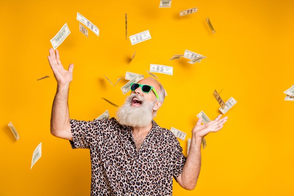 Senior man wearing sunglasses and throwing money in the air
