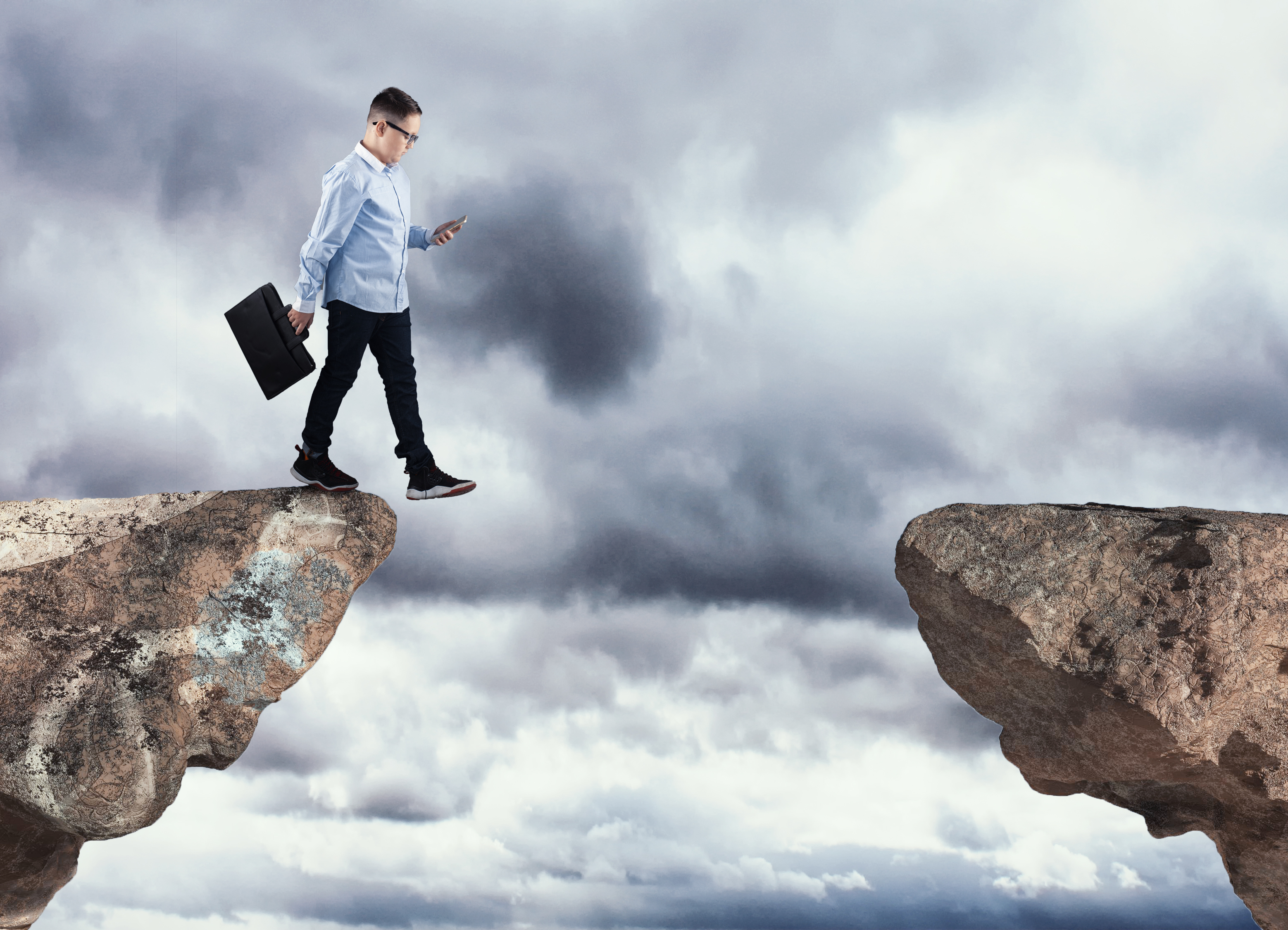 Man looking at smart phone about to walk off a cliff.