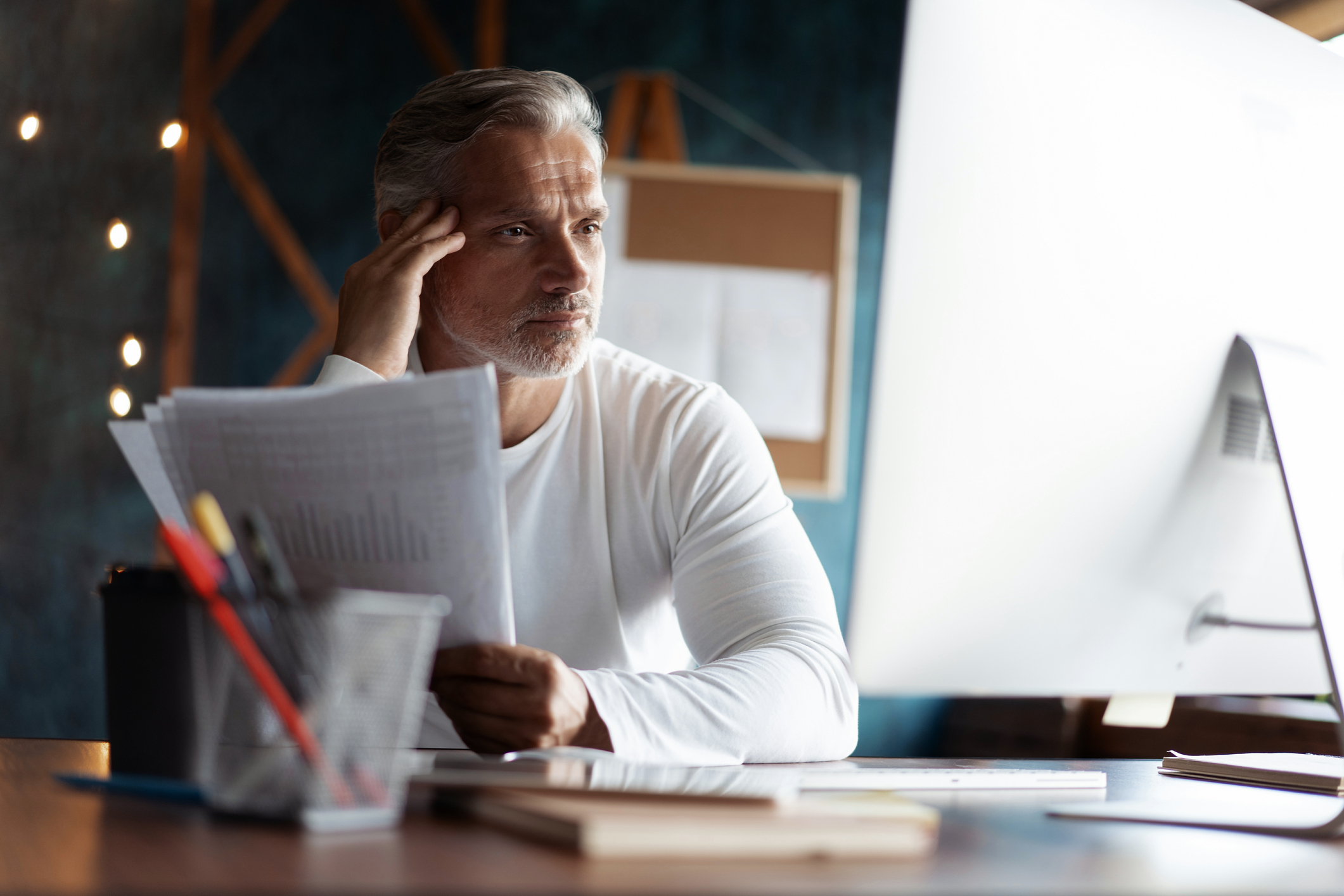 Older person with serious expression holding documents
