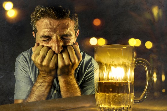 Man cringing next to a pitcher of beer