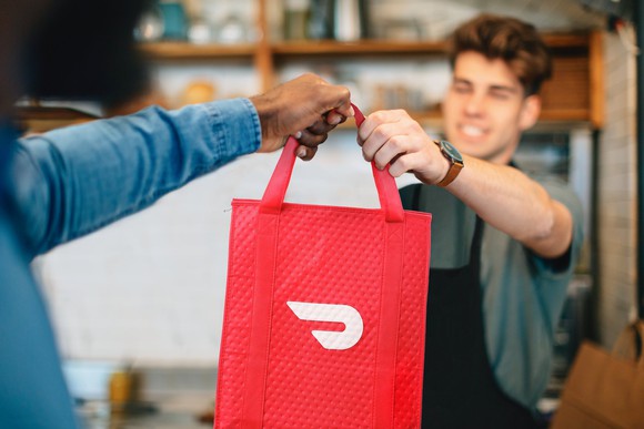 A Dasher picks up an order at a restaurant.