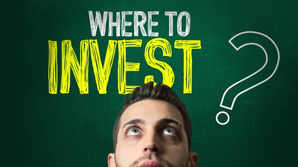 A person looking up at the words "Where to invest?" written on a chalkboard above their head. 